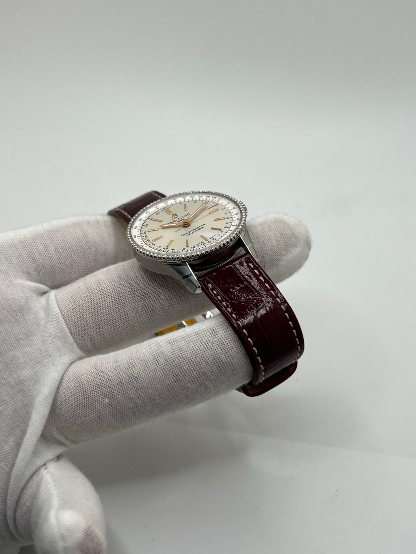 Montre Breitling Navitimer A17327211G1P1 pour femme, modèle automatique en acier de 36 mm avec cadran argent sans chiffres et verre saphir. Cette montre de luxe dispose du calibre Breitling 17 avec une réserve de marche de 38 heures. Elle est équipée d’un bracelet en cuir bordeaux avec boucle déployante en acier. Montre étanche à 3 ATM, état neuf, jamais portée, sans coffret ni papiers d’origine.
