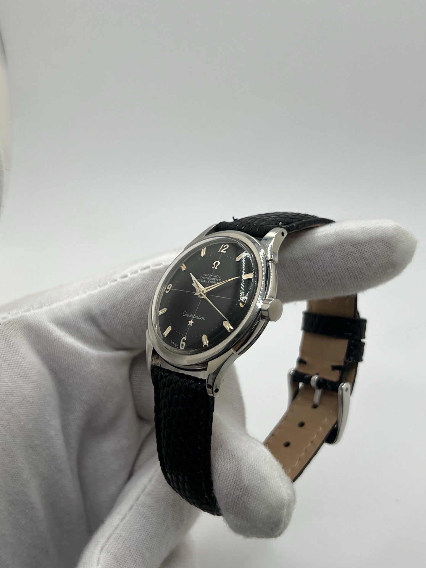 Montre automatique vintage en acier avec boîtier rond de 35 mm, cadran noir à chiffres arabes et verre plexiglas. Modèle chronomètre des années 1950 équipé d’un calibre automatique 505 avec réserve de marche de 46 heures. Bracelet en cuir noir avec boucle ardillon en acier. Montre d’occasion présentant des traces d’usure visibles, révisée récemment, sans coffret ni papiers d’origine.