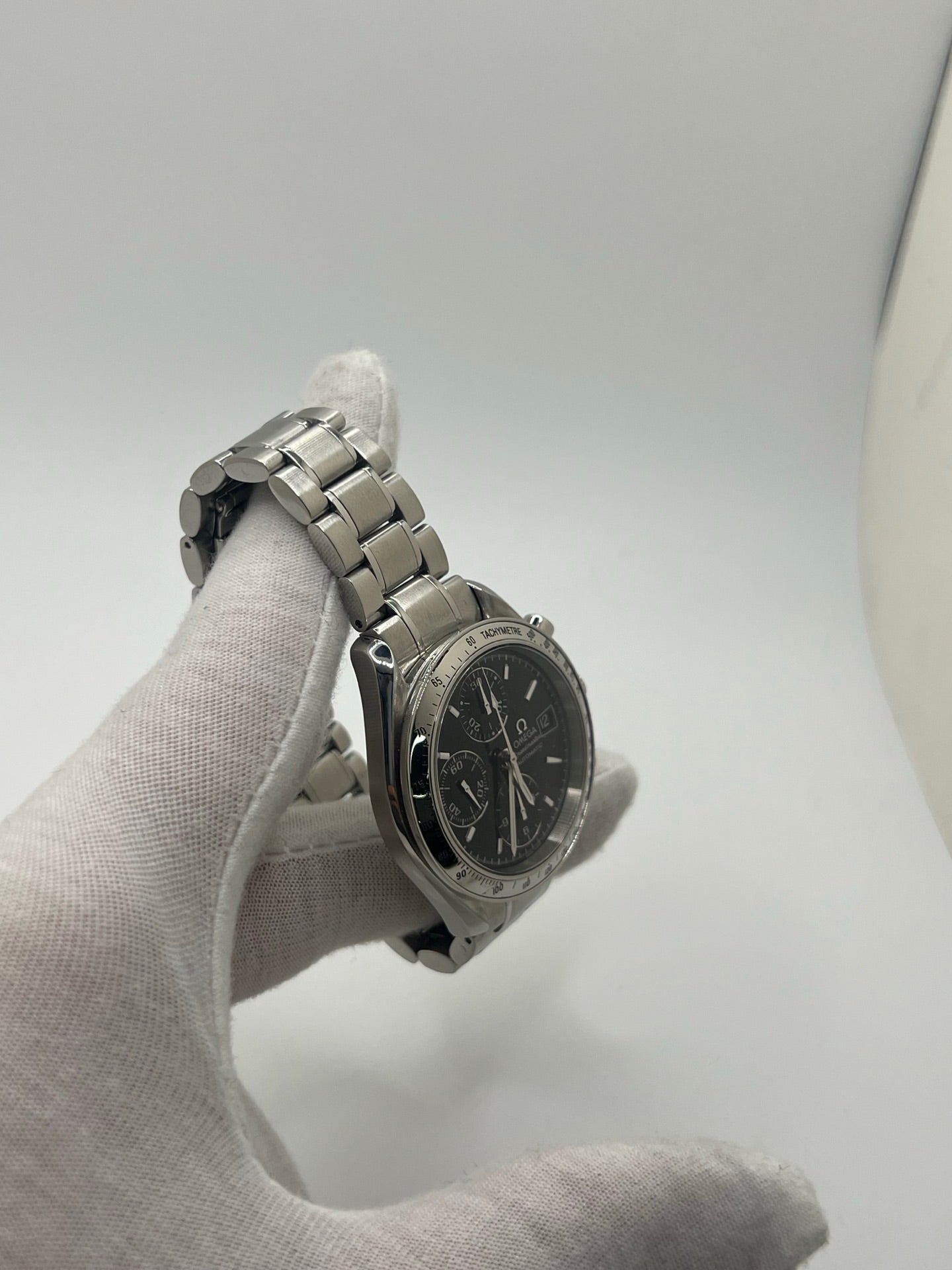 Montre Omega Speedmaster Date référence 3513.50 en acier, chronographe automatique avec boîtier de 39 mm et bracelet en acier assorti. Cadran noir sobre sans chiffres, protégé par un verre saphir, avec affichage de la date et fonctions chronographe. Modèle étanche 5 ATM, animé par le calibre automatique 1152 offrant 44 heures de réserve de marche. Montre homme élégante et sportive, emblématique de la collection Speedmaster.