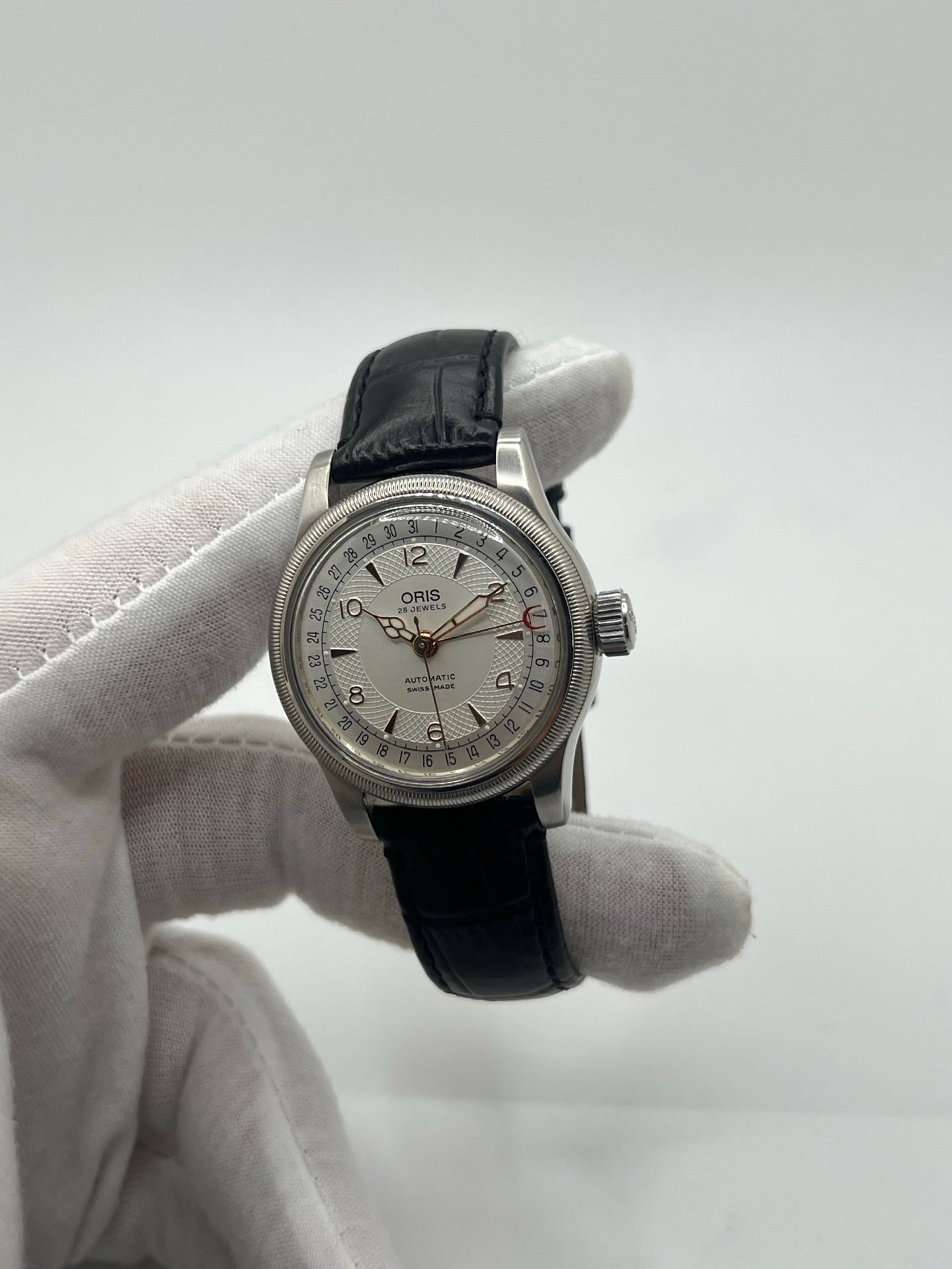 Montre mécanique automatique pour homme au style vintage, dotée d’un boîtier en acier de 36 mm et d’un cadran argent à chiffres arabes lisibles. Modèle équipé d’une fonction date par aiguille centrale, verre en matière plastique et lunette en acier. Bracelet noir avec boucle ardillon en acier. Montre d’occasion en très bon état, présentant de légères traces d’usure superficielles, récemment révisée, idéale pour les amateurs d’horlogerie classique.