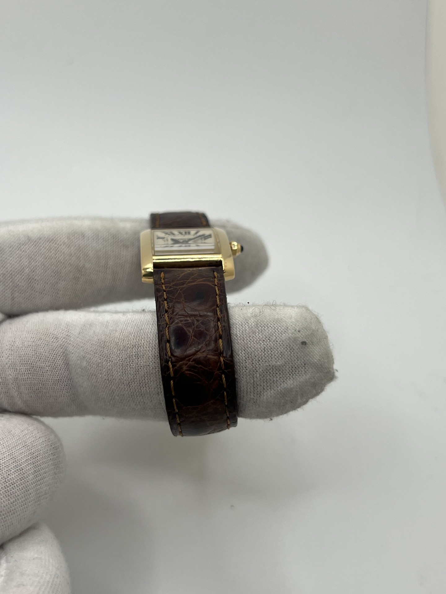 Montre Cartier Tank Française référence 1820 en or jaune 18K, petit modèle pour femme, boîtier rectangulaire emblématique aux lignes droites et élégantes, cadran blanc avec chiffres romains noirs, minuterie chemin de fer et aiguilles bleuies en forme de glaive. Bracelet intégré en acier avec boucle déployante. Mouvement quartz précis. Montre de luxe intemporelle, raffinée et iconique, idéale pour un porté quotidien ou une tenue habillée.
