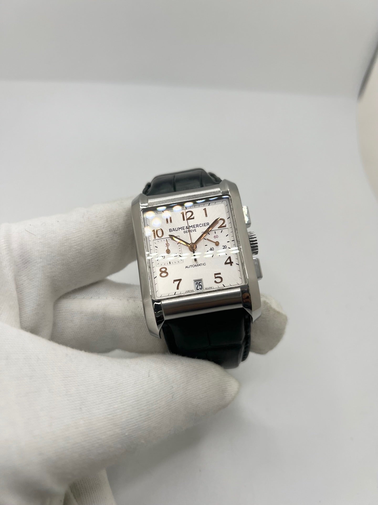 Montre Baume & Mercier Hampton réf. 65698, modèle automatique pour homme ou unisexe. Boîtier en acier de 34,5 mm avec verre saphir résistant aux rayures. Cadran argent avec index en chiffres arabes, offrant une lecture élégante et classique. Bracelet en cuir vert avec boucle déployante en acier. Fonction chronographe et date. Montre de luxe d’occasion en très bon état, avec légères traces d’usure. Révisée le 24 juin 2026 en interne. Livrée sans coffret ni papiers. Disponible à Paris.