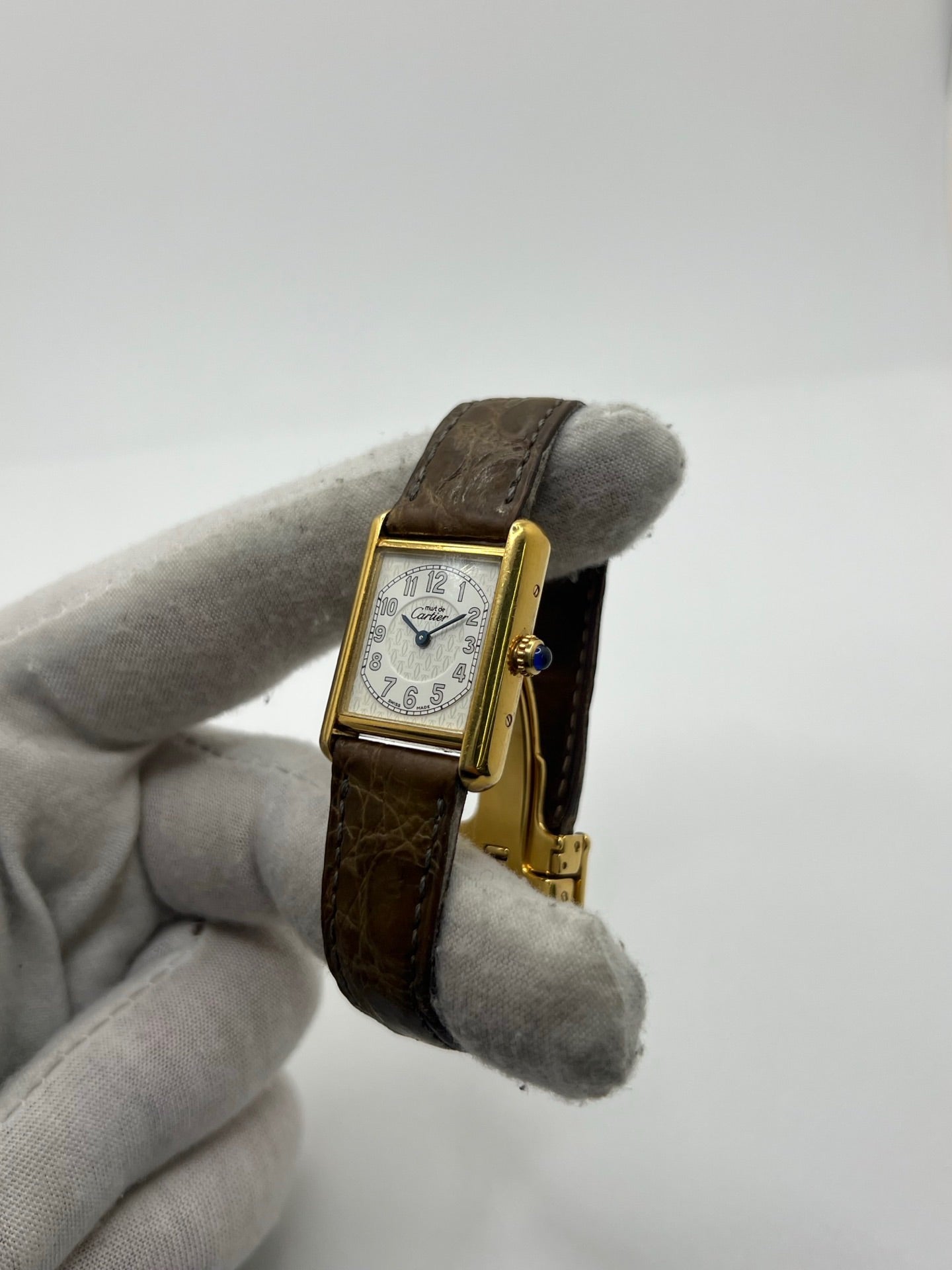 Montre Cartier Tank Vermeil 2415 pour femme, équipée d’un mouvement quartz et d’un boîtier en argent de 22 x 29 mm. Ce modèle d’occasion en bon état présente des traces d’usure visibles, un cadran blanc à chiffres arabes, un verre minéral et un bracelet en cuir brun avec boucle ardillon en argent. Élégante et classique, la Cartier Tank Vermeil 2415 séduit par son design intemporel, idéale pour les passionnées de montres de luxe.