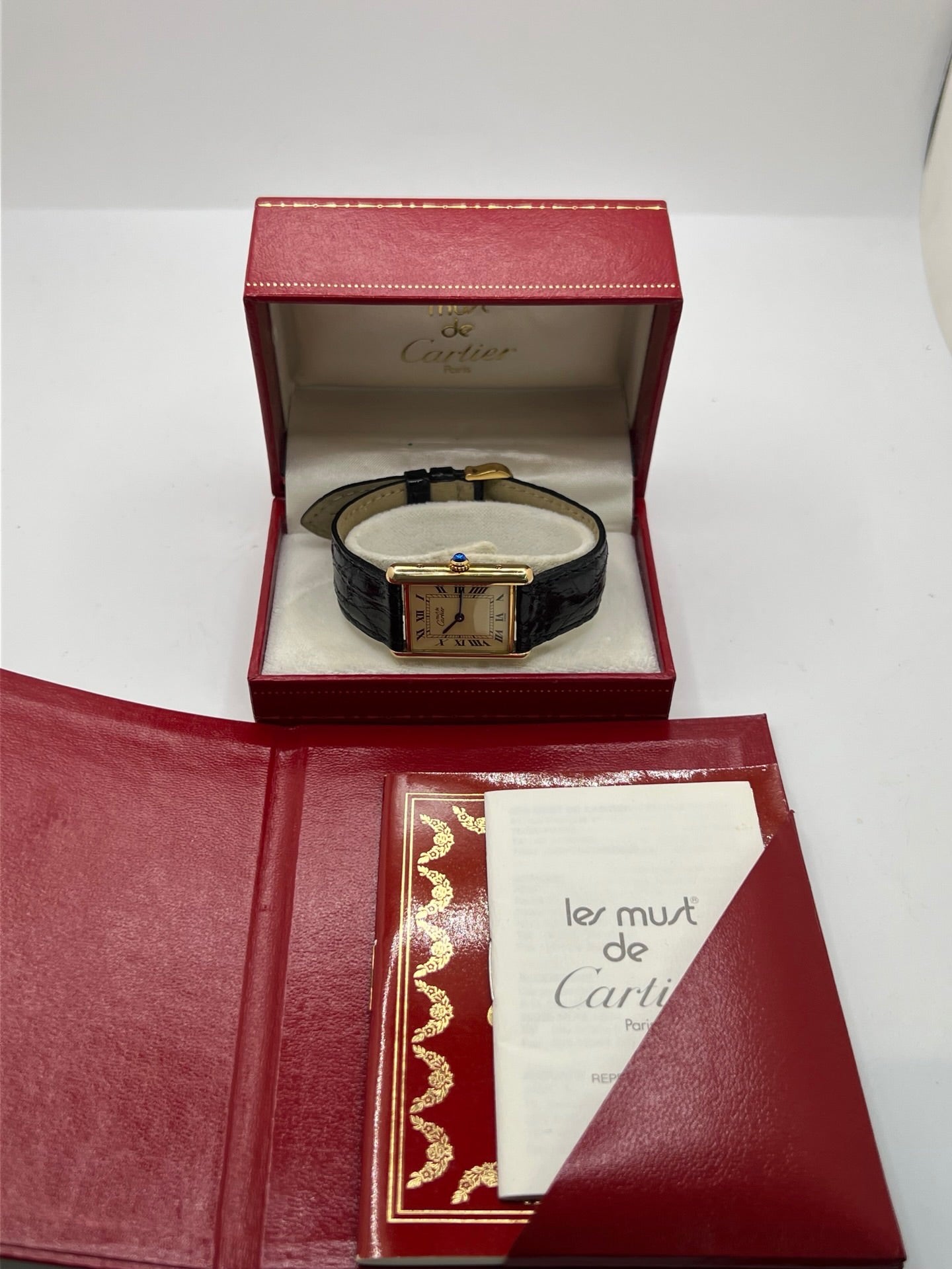 Montre Cartier Tank Vermeil réf. 590005 en argent avec mouvement à quartz, cadran champagne à chiffres romains et verre saphir. Ce modèle emblématique est monté sur un bracelet en cuir de crocodile noir avec boucle ardillon en acier. Son boîtier de 23 × 30 mm offre une élégance intemporelle. Cette montre Cartier Tank Vermeil d'occasion est en très bon état, révisée en interne et livrée avec son coffret d'origine.