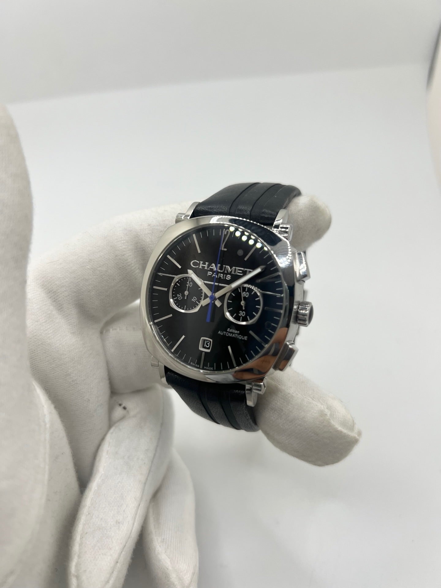 Montre Chaumet Dandy réf. 1229 pour homme ou unisexe, dotée d’un mouvement automatique. Boîtier en acier de 40 mm avec lunette assortie et verre saphir résistant aux rayures. Cadran noir à index bâtons, fonction chronographe et affichage de la date. Bracelet en cuir noir avec boucle déployante en acier. Montre de luxe d’occasion en très bon état, présentant de légères traces d’usure. Révisée en interne le 23 juin 2026, livrée avec coffret d’origine, sans papiers. Disponible à Paris. 