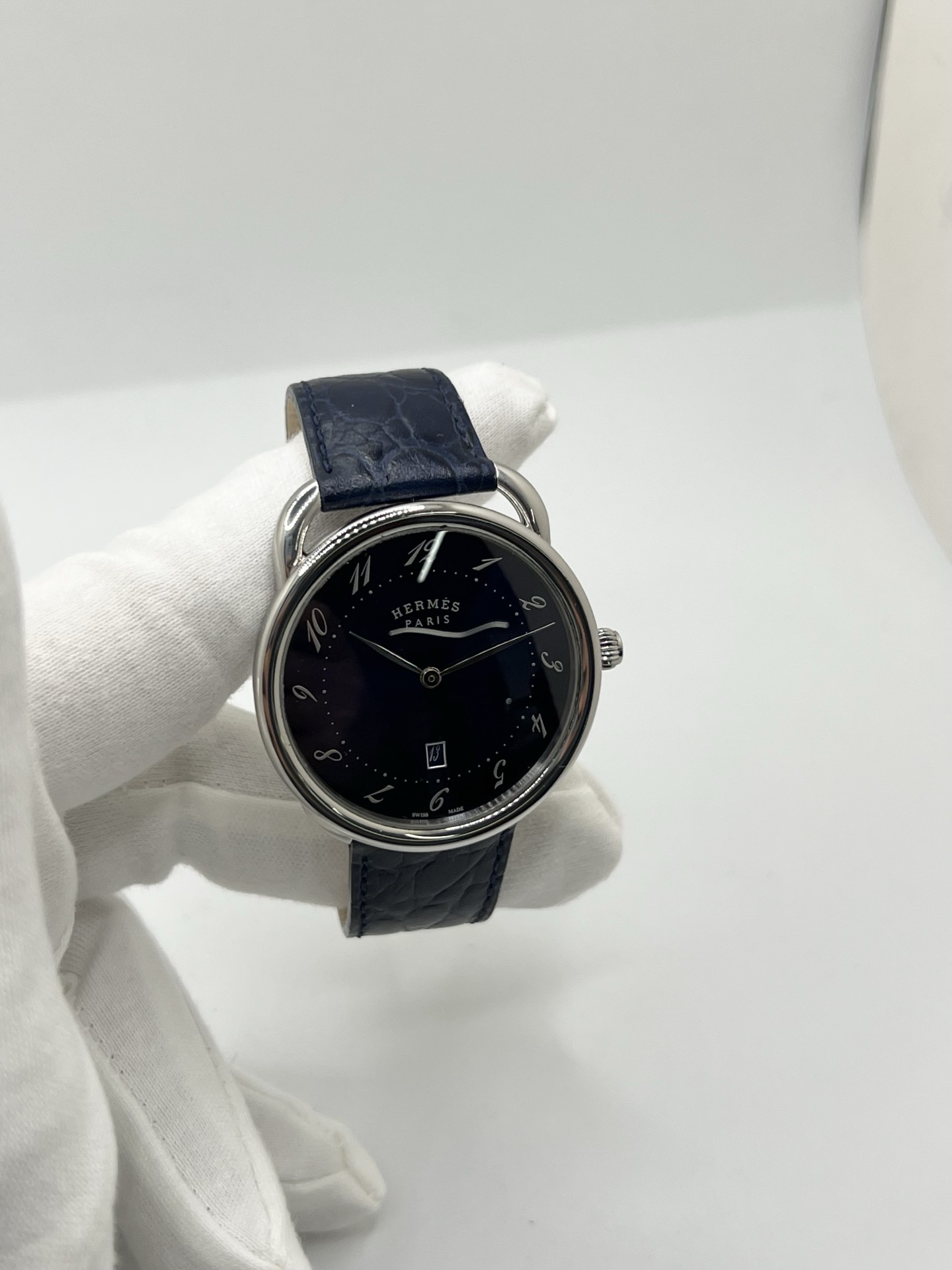 Montre Hermès Arceau grand modèle AR7Q.810 en acier avec cadran blanc épuré, chiffres arabes inclinés signature de la collection Arceau, mouvement quartz précis et bracelet en cuir élégant. Design intemporel et raffiné, idéal pour une tenue chic au quotidien ou une occasion spéciale, alliant savoir-faire horloger et esthétique minimaliste.