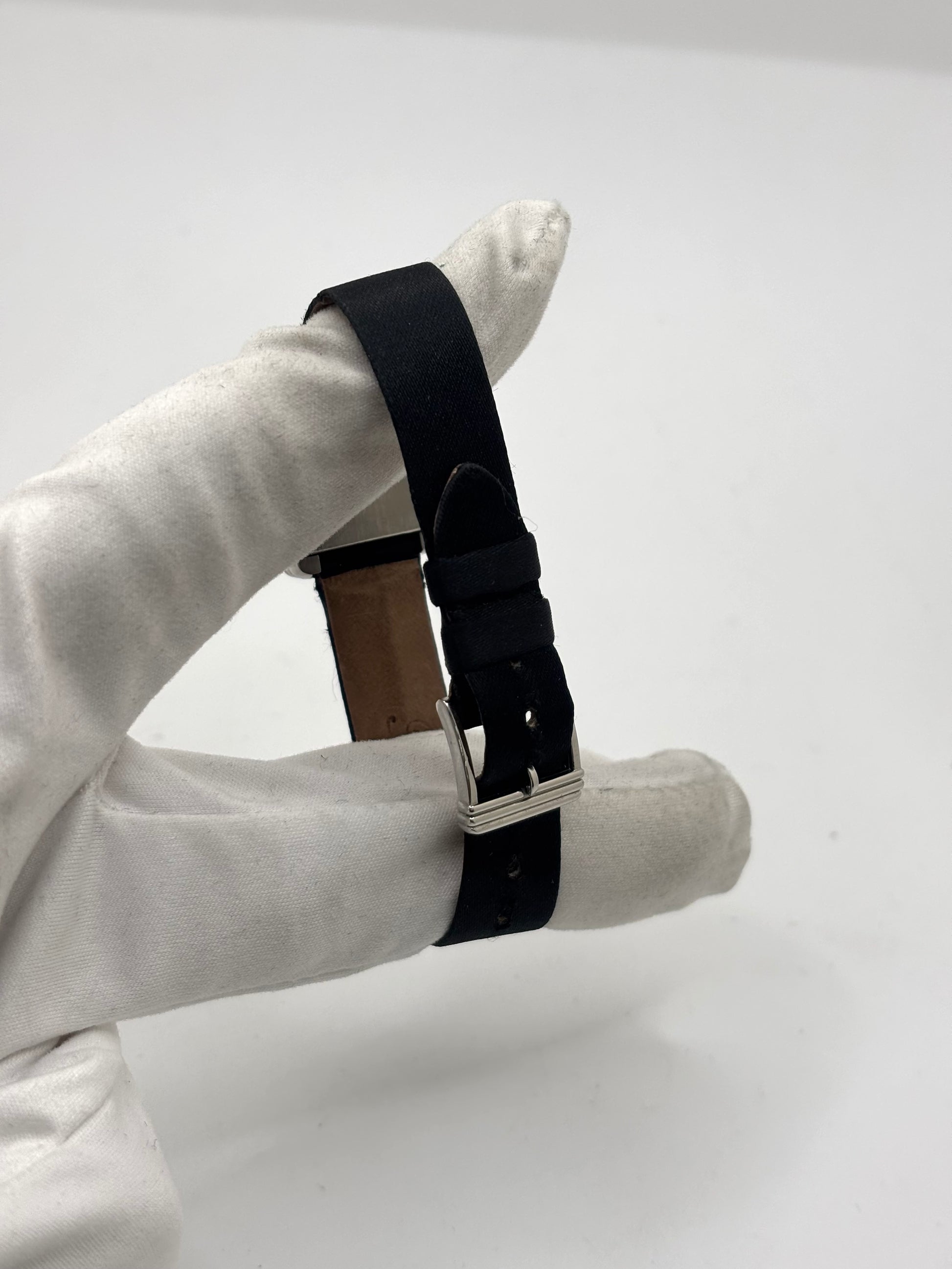 Montre Poiray Ma Première petit modèle en acier avec boîtier de 21,30 × 18,20 mm, cadran blanc épuré sans chiffres et verre minéral. Animée par un mouvement quartz, cette montre femme est équipée de son bracelet textile noir et de sa boucle ardillon d'origine en acier. Révisée, en excellent état et garantie 1 an, cette montre de luxe au style intemporel incarne l'élégance parisienne et le savoir-faire horloger de la maison Poiray.