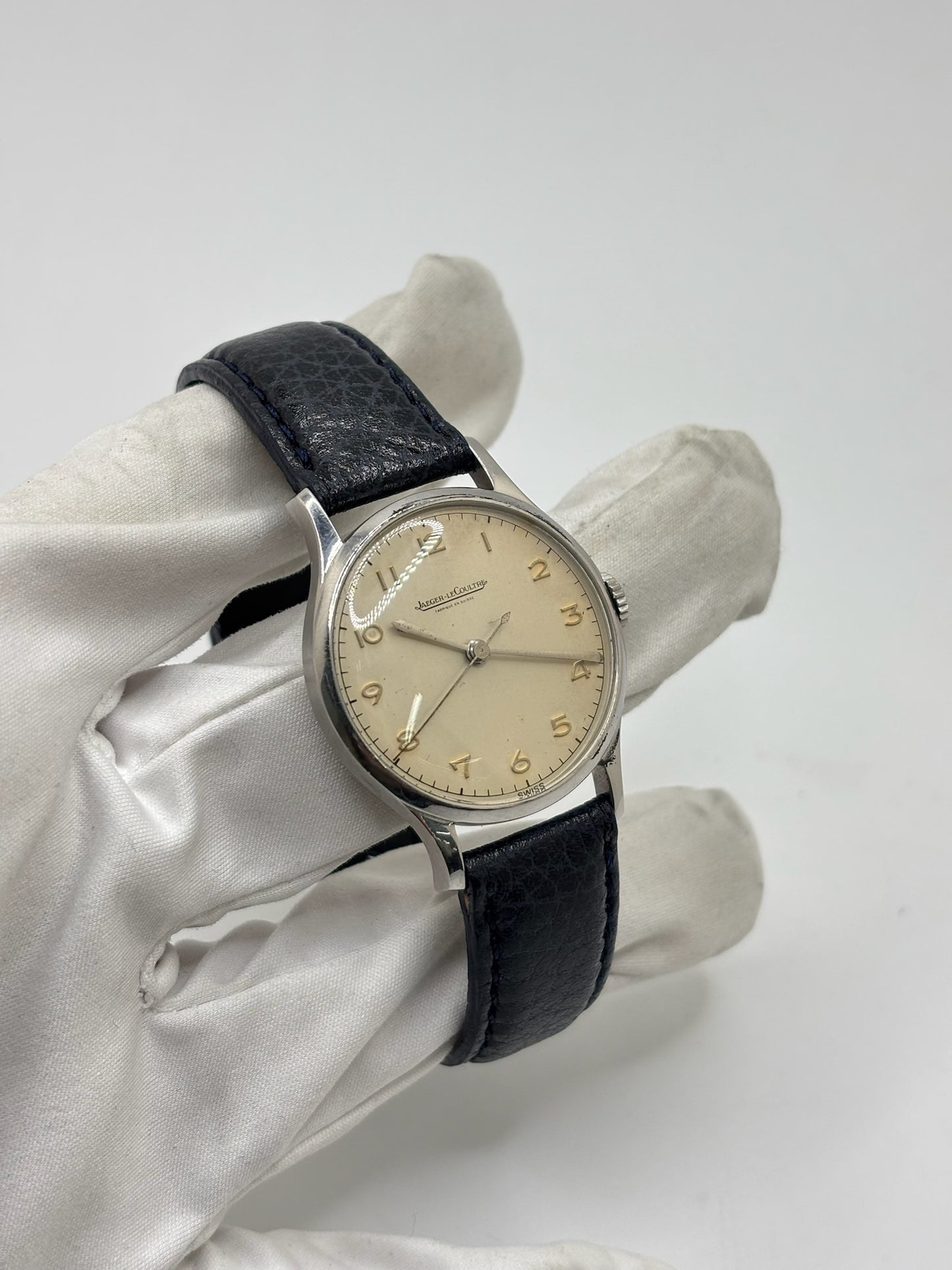Montre Jaeger-LeCoultre vintage en acier datant des années 1950, équipée du calibre P478 à remontage manuel. Son cadran argent à chiffres arabes est protégé par un verre plexiglas et associé à un bracelet en cuir noir. Avec son boîtier de 31,5 mm et son design sobre et élégant, cette montre mécanique de collection illustre le savoir-faire horloger suisse de l'époque. Pièce ancienne recherchée par les amateurs de montres vintage et de garde-temps de caractère.
