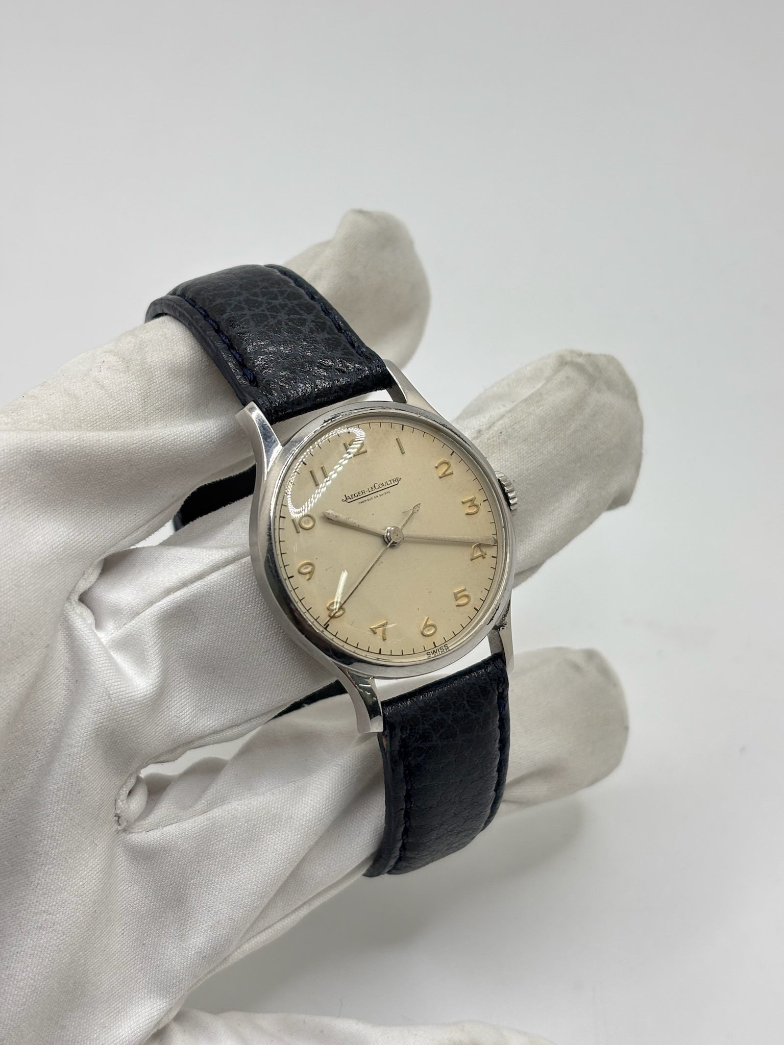 Montre Jaeger-LeCoultre vintage en acier datant des années 1950, équipée du calibre P478 à remontage manuel. Son cadran argent à chiffres arabes est protégé par un verre plexiglas et associé à un bracelet en cuir noir. Avec son boîtier de 31,5 mm et son design sobre et élégant, cette montre mécanique de collection illustre le savoir-faire horloger suisse de l'époque. Pièce ancienne recherchée par les amateurs de montres vintage et de garde-temps de caractère.
