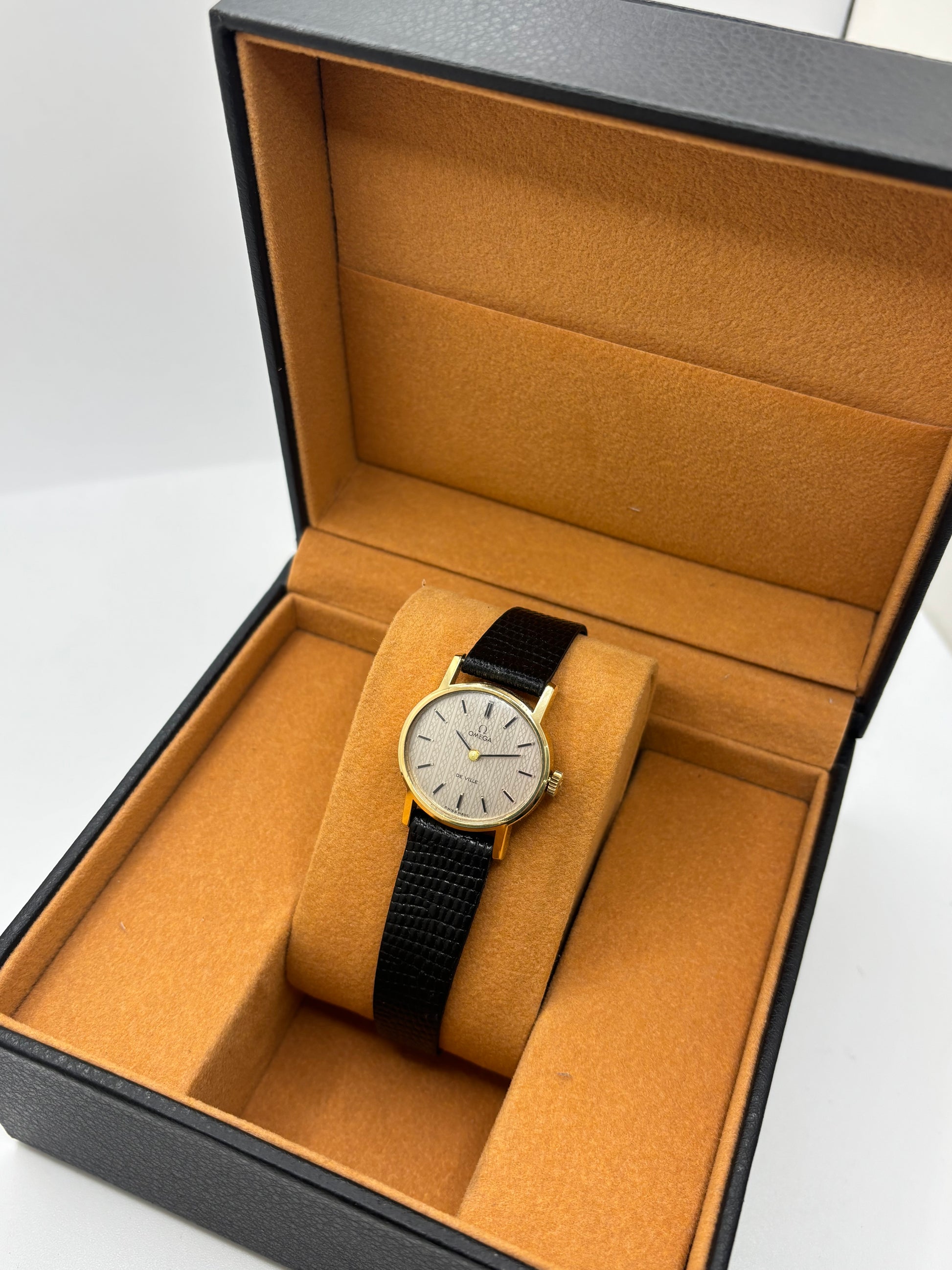 Montre Omega De Ville vintage référence 511.0508 pour femme, datant de 1967, avec boîtier en acier de 24 mm et cadran gris à index bâtons. Cette montre à remontage manuel est équipée du calibre Omega 625 à 17 rubis et est montée sur un bracelet en cuir noir avec boucle ardillon en acier. Révisée et en très bon état, elle présente de légères traces d'usure conformes à son âge. Une montre de collection au design élégant, idéale pour les amateurs d'horlogerie vintage.
