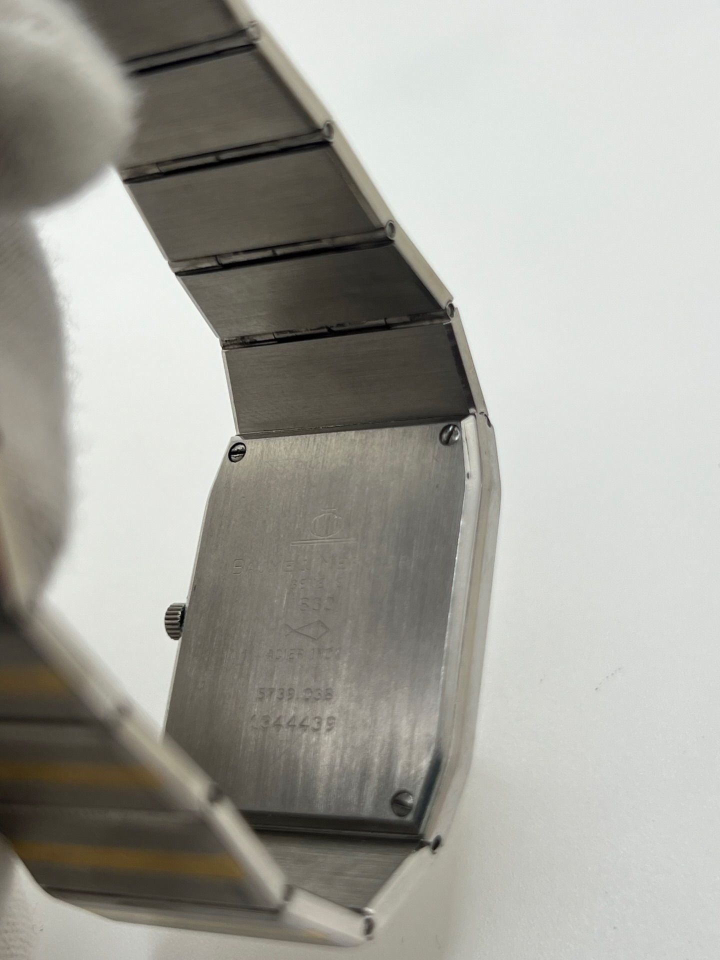 Montre Baume & Mercier Carlo Zebra 5739.038 pour homme/unisexe, mouvement quartz, boîtier acier 25x32 mm, cadran or, verre saphir et bracelet or/acier avec boucle pli. Étanche 10 ATM, d'occasion en bon état, disponible sans coffret ni papiers d'origine. Idéale pour les amateurs de montres de luxe élégantes et intemporelles.