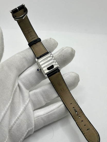 Montre Cartier Tank Must PM WSTA0042 pour femme, modèle élégant de la collection Tank datant de 2021. Cette montre de luxe se distingue par son boîtier rectangulaire en acier de 22 x 29 mm, son cadran argenté, son verre saphir et son bracelet en cuir noir. Équipée d’un mouvement à quartz, la Cartier Tank Must PM allie sobriété et élégance intemporelle. Proposée d’occasion en très bon état, elle est vendue avec son coffret d’origine et a bénéficié d’une révision interne le 19 octobre 2026.