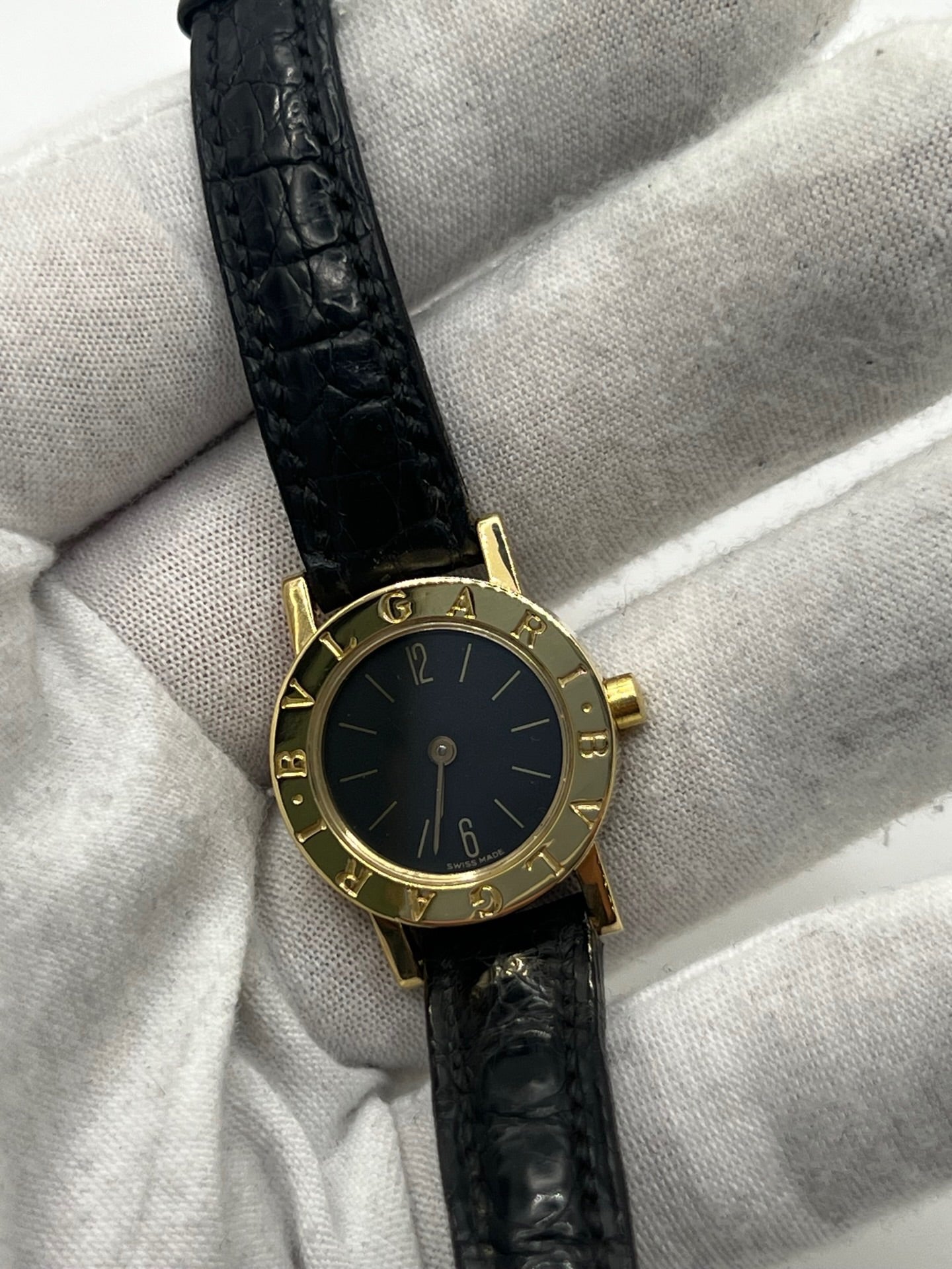 Montre femme Bulgari Bulgari Lady BB 23 GL en or jaune avec boîtier rond de 23 mm, cadran noir élégant et verre saphir. Cette montre de luxe à mouvement quartz est dotée d’un bracelet en cuir noir avec boucle ardillon en or jaune. Modèle emblématique au design intemporel, idéal pour un poignet féminin, alliant raffinement, précision et savoir-faire horloger italien. Parfaite comme montre habillée ou pièce de collection.