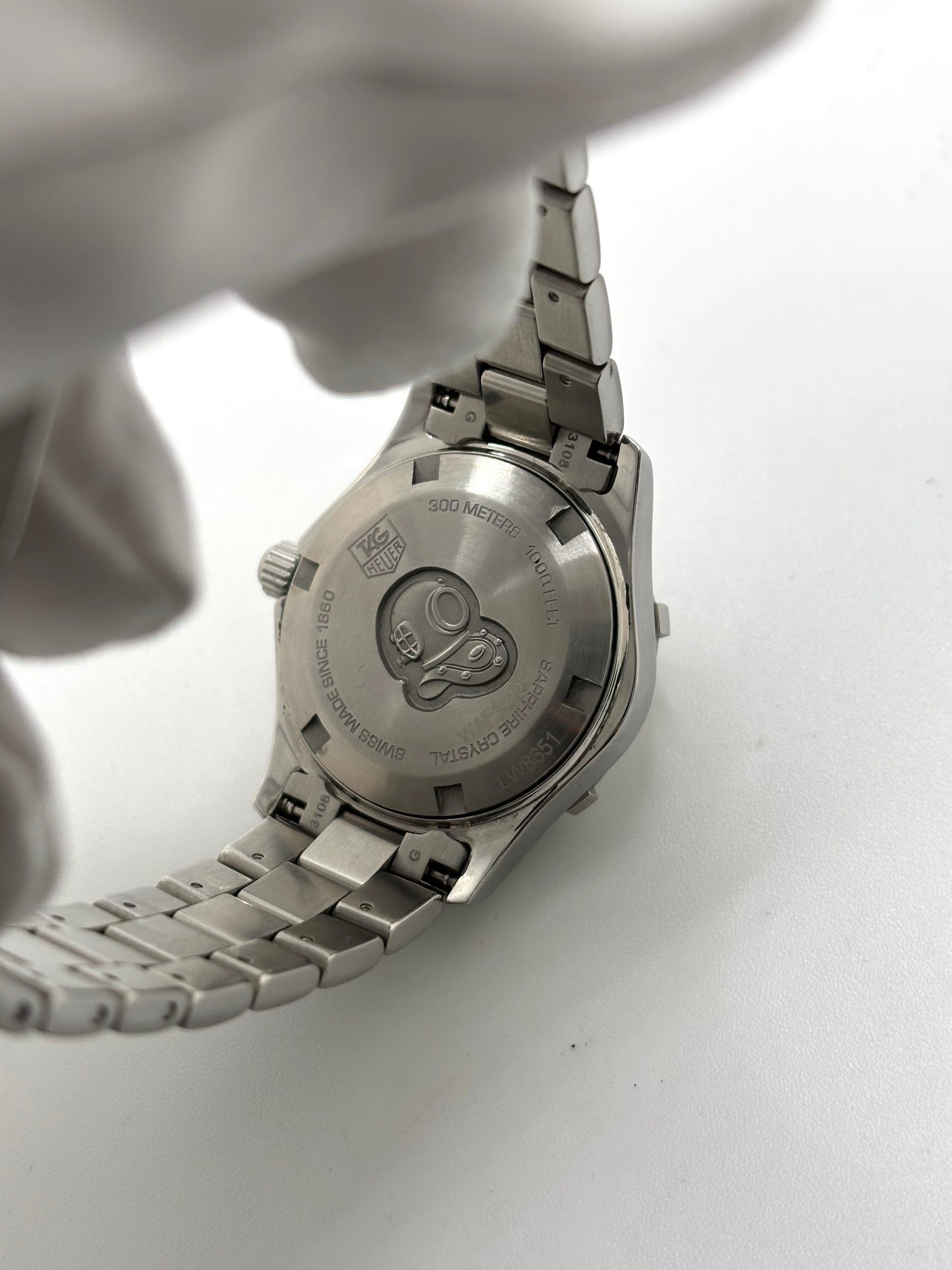 Montre femme TAG Heuer Aquaracer Lady référence WAF1412 en acier avec boîtier 27 mm et bracelet acier. Cadran argent avec chiffres arabes, mouvement quartz précis et étanchéité 30 ATM. Montre de luxe sportive et élégante en très bon état, révisée en 2026, idéale pour un usage quotidien ou une tenue habillée. Détail du boîtier acier poli, montre horlogère suisse féminine, intemporelle et raffinée.