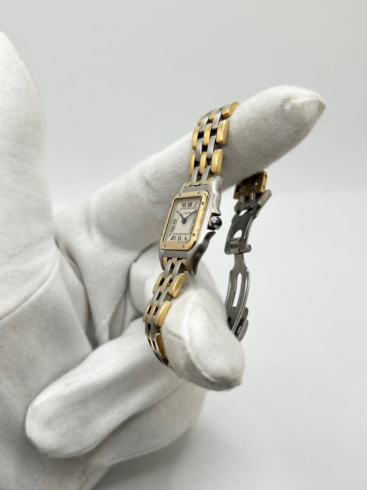 Montre Cartier Panthère 1057917 pour femme, modèle emblématique de la maison Cartier datant de 1989. Cette montre de luxe vintage associe élégamment l’or et l’acier, avec un cadran blanc raffiné, un verre saphir et un mouvement à quartz. La Cartier Panthère référence 1057917 est proposée d’occasion en très bon état, avec son coffret et ses papiers d’origine. Révisée en interne le 19 octobre 2026, cette montre Cartier Panthère en or et acier allie élégance intemporelle et savoir-faire horloger.