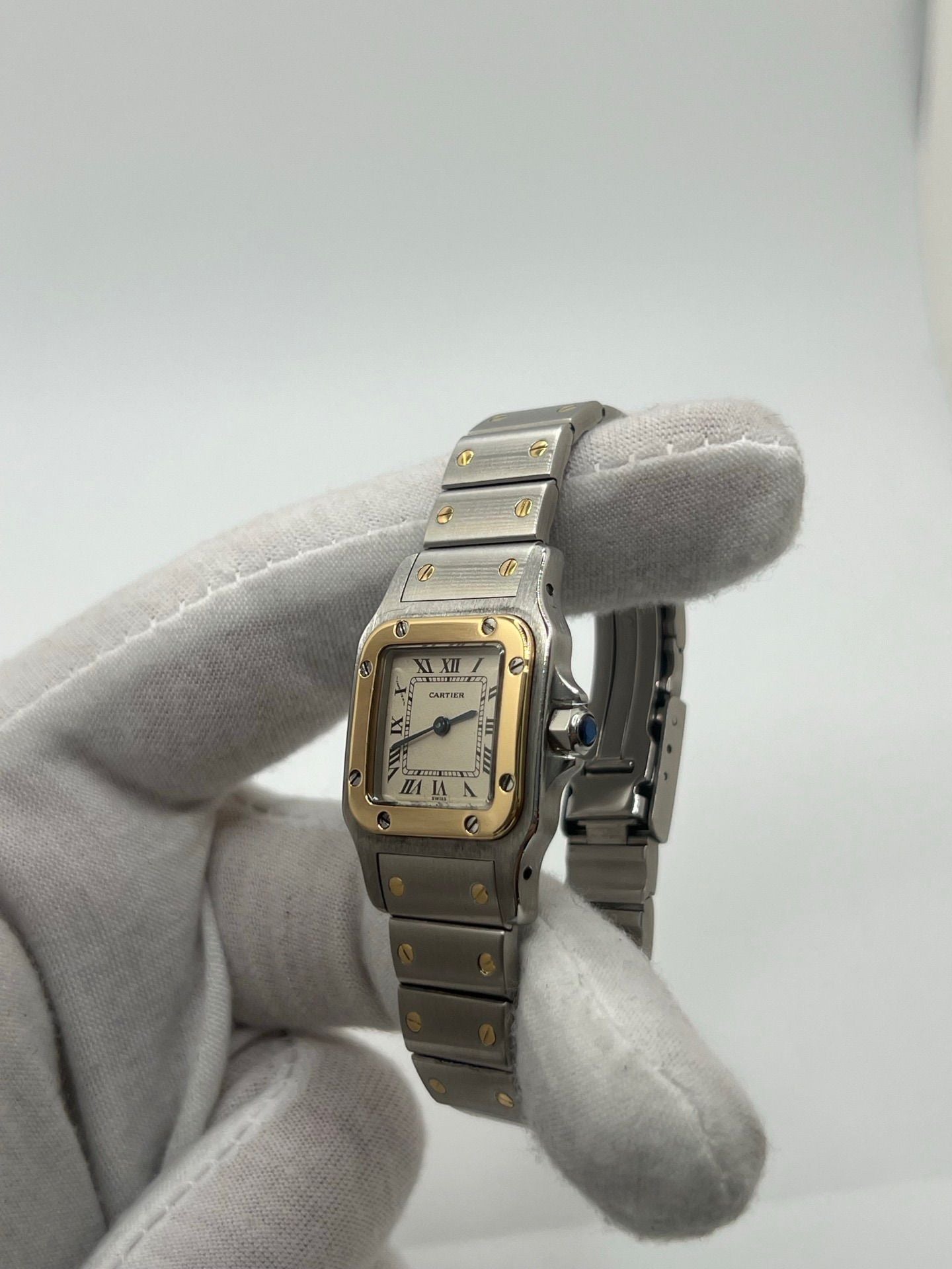 Montre Cartier Santos Galbée Lady référence 1057930 en or et acier, format 24 x 35 mm, équipée d’un mouvement quartz calibre 157. Modèle pour femme avec cadran blanc à chiffres romains, bracelet assorti et verre saphir. Pièce d’occasion en très bon état avec légères traces d’usage, livrée avec coffret d’origine.