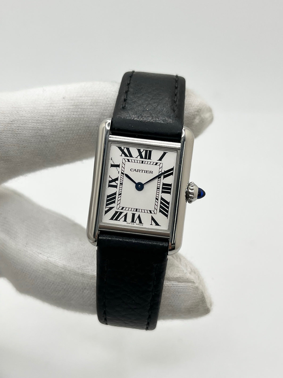 Montre Cartier Tank Must PM WSTA0042 pour femme, modèle élégant de la collection Tank datant de 2021. Cette montre de luxe se distingue par son boîtier rectangulaire en acier de 22 x 29 mm, son cadran argenté, son verre saphir et son bracelet en cuir noir. Équipée d’un mouvement à quartz, la Cartier Tank Must PM allie sobriété et élégance intemporelle. Proposée d’occasion en très bon état, elle est vendue avec son coffret d’origine et a bénéficié d’une révision interne le 19 octobre 2026.