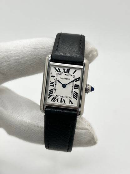 Montre Cartier Tank Must PM WSTA0042 pour femme, modèle élégant de la collection Tank datant de 2021. Cette montre de luxe se distingue par son boîtier rectangulaire en acier de 22 x 29 mm, son cadran argenté, son verre saphir et son bracelet en cuir noir. Équipée d’un mouvement à quartz, la Cartier Tank Must PM allie sobriété et élégance intemporelle. Proposée d’occasion en très bon état, elle est vendue avec son coffret d’origine et a bénéficié d’une révision interne le 19 octobre 2026.