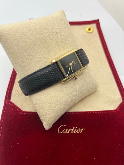 Montre Cartier Tank Must Vermeil référence 5057001 pour femme, boîtier en argent 20 x 28 mm, cadran noir sans chiffres et bracelet en cuir de lézard noir. Modèle à mouvement quartz, en bon état avec traces d’usure légères. Montre élégante au style intemporel, idéale pour un look sophistiqué et raffiné. Parfaite pour les amateurs de pièces vintage.