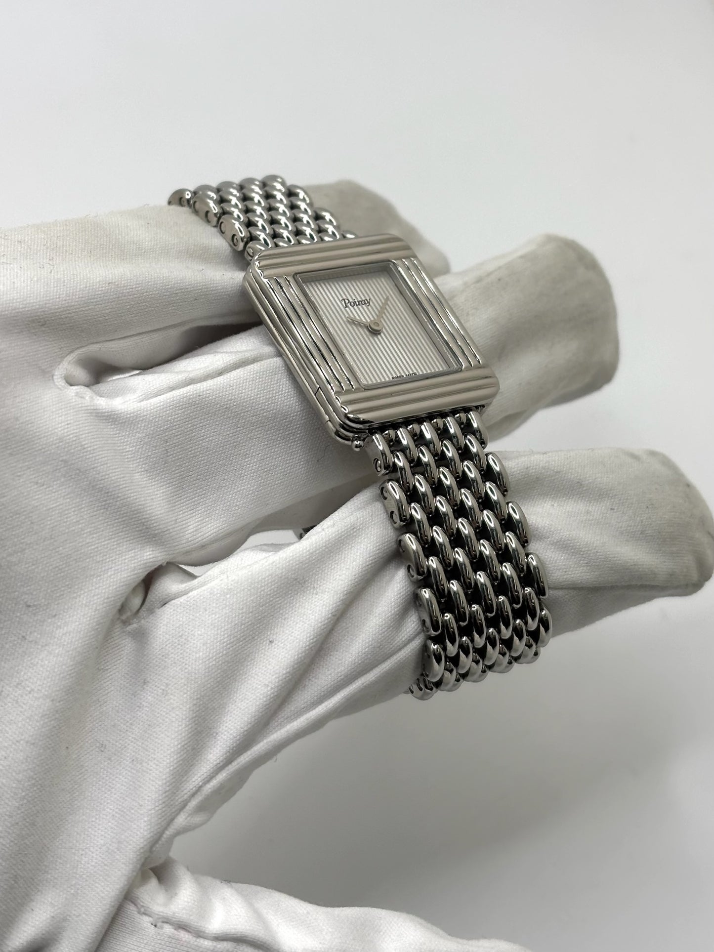 Montre Poiray Ma Première pour femme en acier inoxydable avec boîtier rectangulaire de 22,5 x 26 mm. Cette montre quartz arbore un cadran argenté protégé par un verre saphir et un bracelet en acier à boucle double pliant. Élégante et intemporelle, cette montre de luxe féminine d'occasion séduit par son design emblématique et sa finition raffinée. Modèle iconique de la maison Poiray, idéal pour les amateurs d'horlogerie et de joaillerie française.
