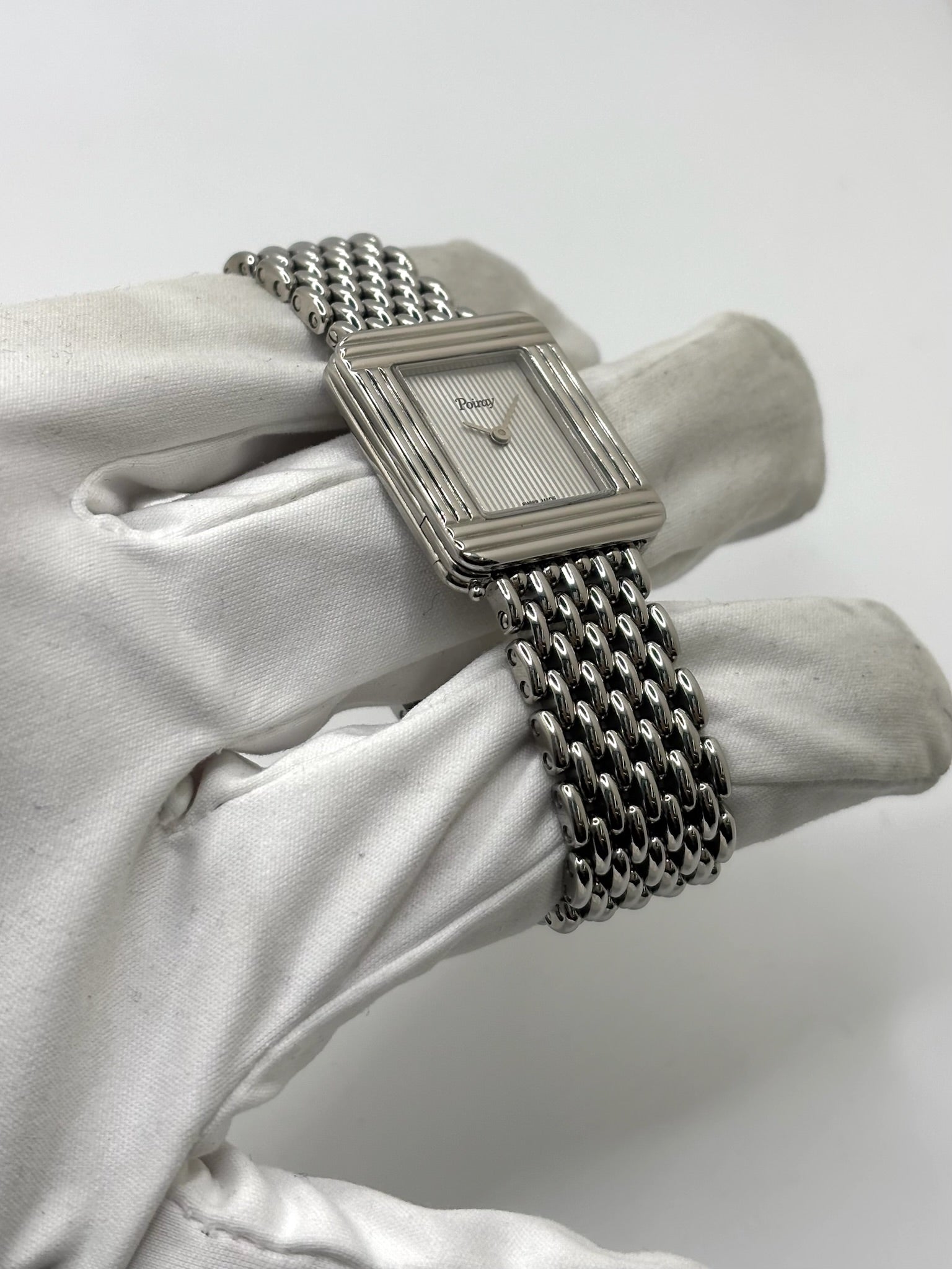 Montre Poiray Ma Première pour femme en acier inoxydable avec boîtier rectangulaire de 22,5 x 26 mm. Cette montre quartz arbore un cadran argenté protégé par un verre saphir et un bracelet en acier à boucle double pliant. Élégante et intemporelle, cette montre de luxe féminine d'occasion séduit par son design emblématique et sa finition raffinée. Modèle iconique de la maison Poiray, idéal pour les amateurs d'horlogerie et de joaillerie française.
