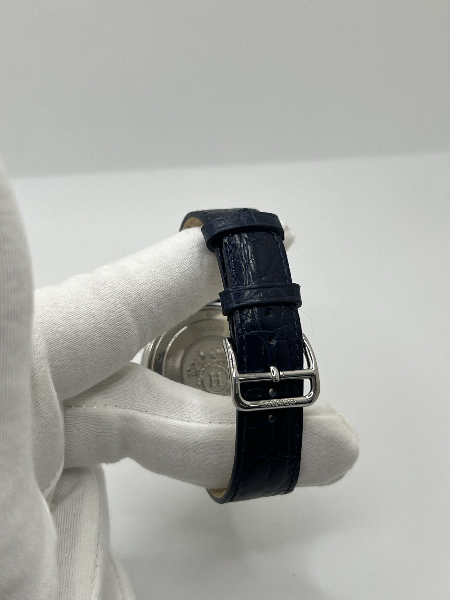 Montre Hermès Arceau grand modèle AR7Q.810 en acier avec cadran blanc épuré, chiffres arabes inclinés signature de la collection Arceau, mouvement quartz précis et bracelet en cuir élégant. Design intemporel et raffiné, idéal pour une tenue chic au quotidien ou une occasion spéciale, alliant savoir-faire horloger et esthétique minimaliste.