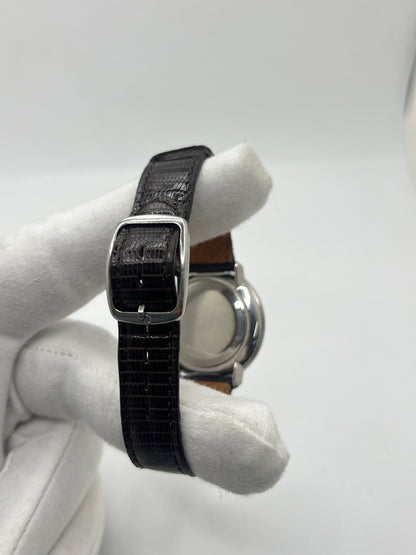 Montre Omega De Ville vintage référence 111.077 en acier, fabriquée en 1969. Ce modèle à remontage manuel est doté d'un cadran argent avec chiffres romains, d'un verre en plexiglas et d'un boîtier de 33 mm. Le bracelet en cuir noir avec boucle ardillon en acier complète son style classique et intemporel. Cette montre d'occasion révisée séduit les amateurs d'horlogerie vintage et de montres Omega de collection.
