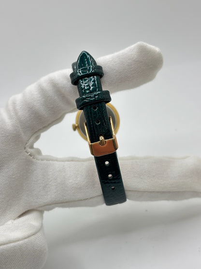 Montre Omega Genève vintage référence 511.0457 pour femme, fabriquée vers 1972 et équipée d'un mouvement à remontage manuel. Son boîtier en acier de 23 mm est associé à un cadran blanc à index bâtons protégé par un verre en matière plastique. Elle est montée sur un bracelet en cuir vert avec boucle ardillon en acier. Révisée en interne et proposée en très bon état, cette montre d'occasion incarne l'élégance discrète et le savoir-faire horloger suisse des années 1970.