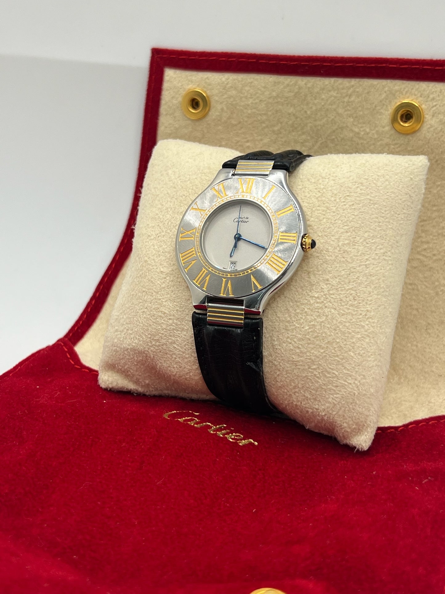 Montre Cartier 21 Must de Cartier avec boîtier 35 mm en or et acier, cadran blanc à chiffres romains, mouvement quartz. Modèle élégant et mixte, équipé d’une boucle déployante sur bracelet cuir noir. Montre de luxe vintage en très bon état, révisée, disponible sans boîte ni papiers d’origine. Idéale pour collectionneur ou amateur de montres emblématiques signées Cartier.