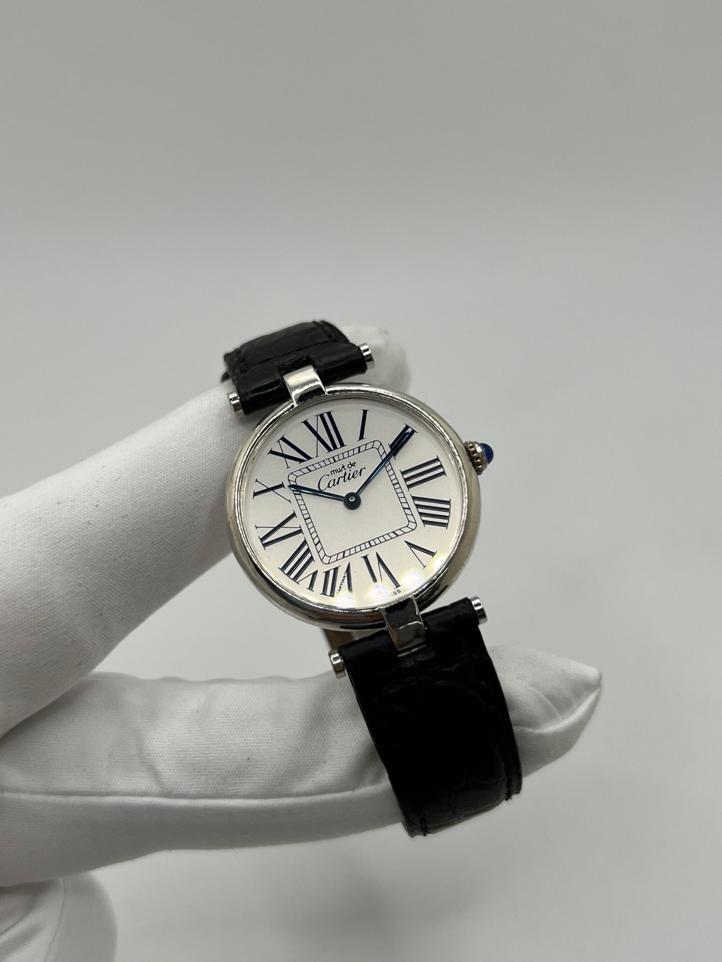 Montre Cartier Must Vendôme référence 1860 avec boîtier rond en argent de 30 mm et cadran argent à chiffres romains signature. Mouvement quartz fiable et élégant, protégé par un verre. Bracelet en cuir noir avec boucle ardillon offrant un porté confortable et raffiné. Modèle emblématique au style classique et intemporel, idéal pour une tenue habillée ou une collection de montres vintage. Montre d’occasion en très bon état, révisée et prête à être portée au quotidien.