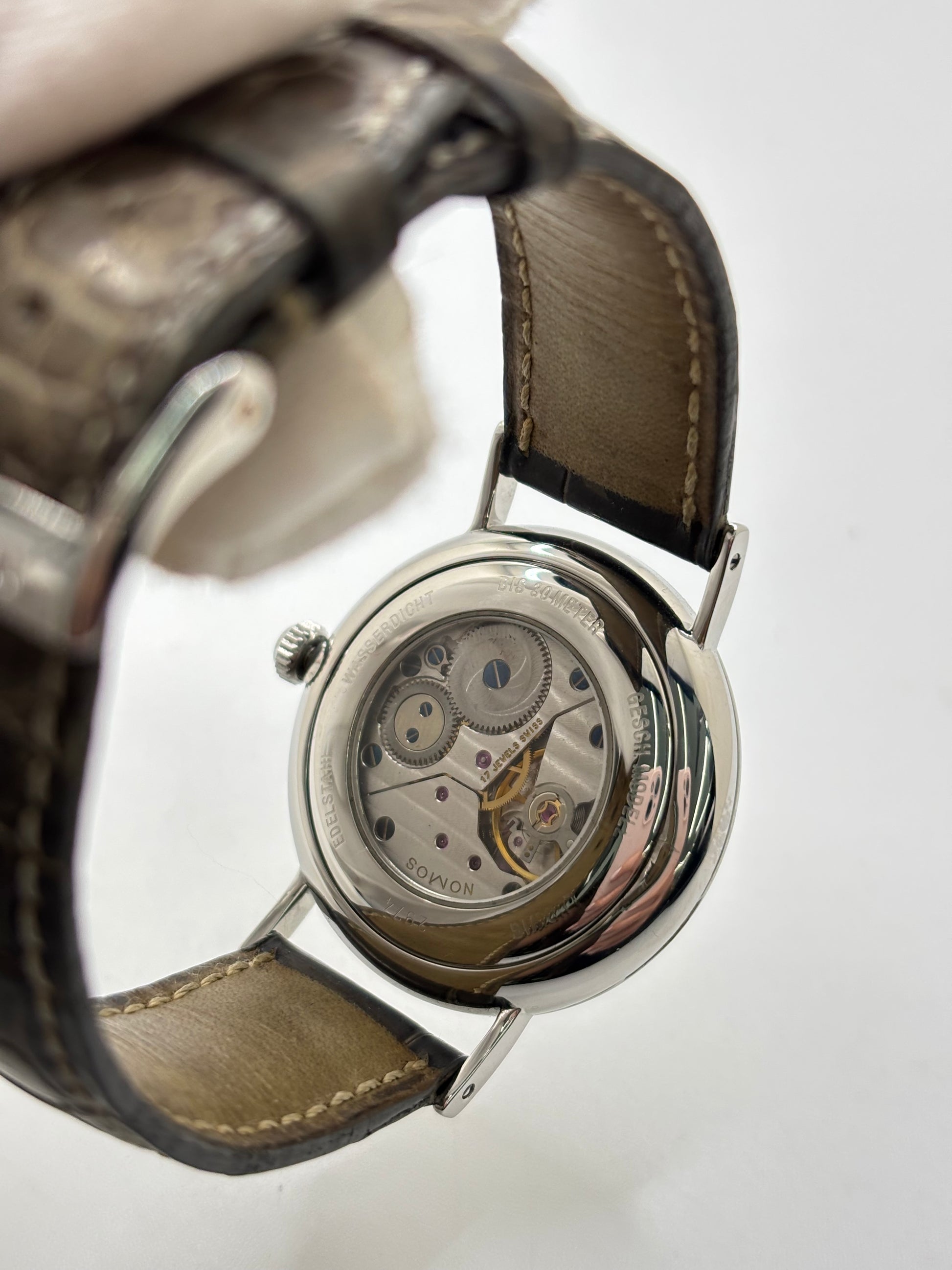 Montre Nomos Glashütte Ludwig 205 en acier avec boîtier de 37,5 mm, mouvement à remontage manuel offrant 43 heures de réserve de marche et cadran blanc à chiffres romains. Équipée d'un verre saphir, d'un bracelet en cuir noir, d'une petite seconde, d'un fond transparent et d'aiguilles en acier bleui, cette montre de luxe d'occasion est en très bon état avec de légères traces d'usure. Un modèle élégant au style intemporel, idéal pour les amateurs d'horlogerie.
