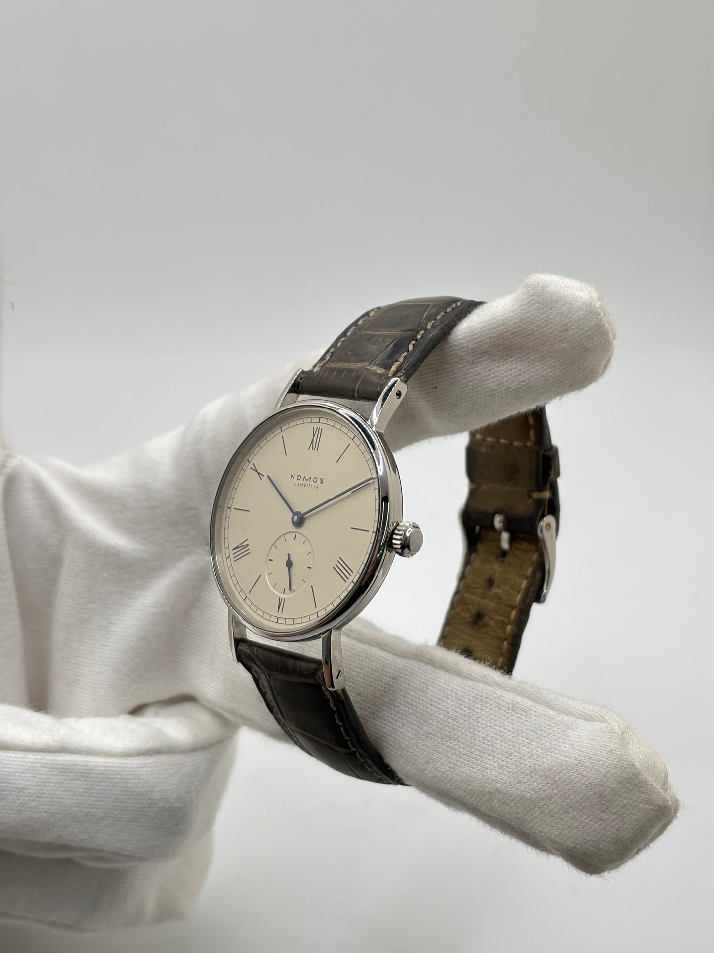 Montre Nomos Glashütte Ludwig 205 en acier avec boîtier de 37,5 mm, mouvement à remontage manuel offrant 43 heures de réserve de marche et cadran blanc à chiffres romains. Équipée d'un verre saphir, d'un bracelet en cuir noir, d'une petite seconde, d'un fond transparent et d'aiguilles en acier bleui, cette montre de luxe d'occasion est en très bon état avec de légères traces d'usure. Un modèle élégant au style intemporel, idéal pour les amateurs d'horlogerie.
