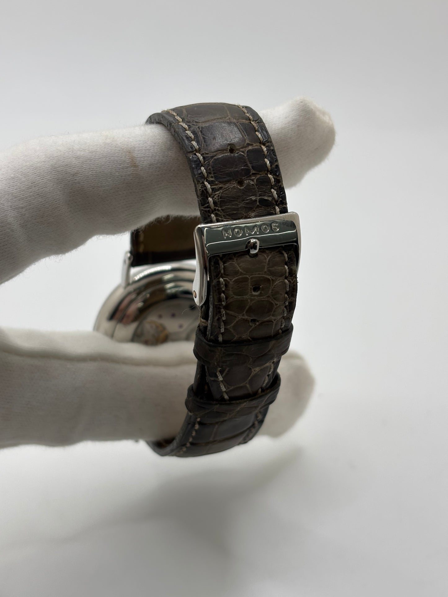 Montre Nomos Glashütte Ludwig 205 en acier avec boîtier de 37,5 mm, mouvement à remontage manuel offrant 43 heures de réserve de marche et cadran blanc à chiffres romains. Équipée d'un verre saphir, d'un bracelet en cuir noir, d'une petite seconde, d'un fond transparent et d'aiguilles en acier bleui, cette montre de luxe d'occasion est en très bon état avec de légères traces d'usure. Un modèle élégant au style intemporel, idéal pour les amateurs d'horlogerie.
