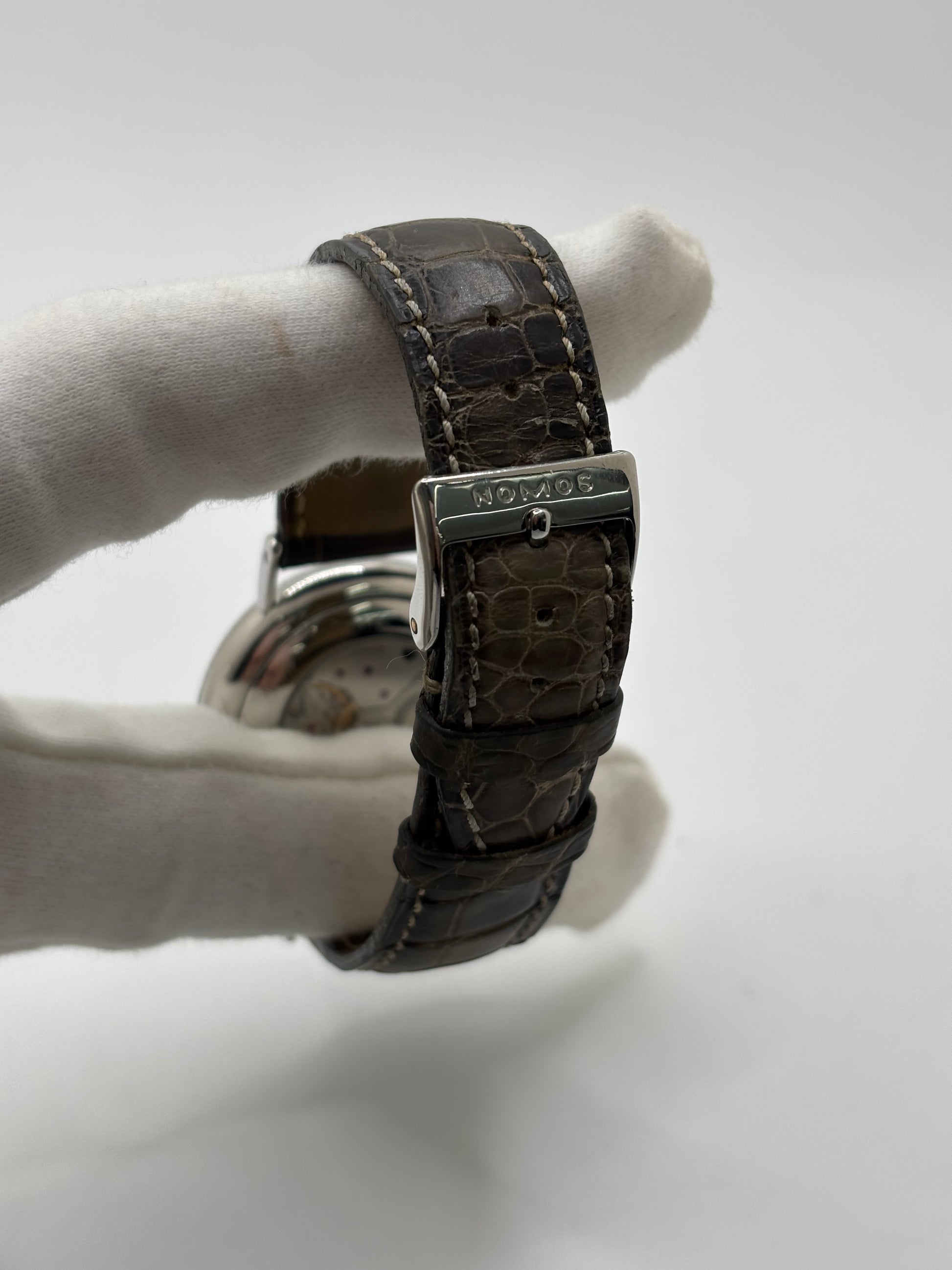 Montre Nomos Glashütte Ludwig 205 en acier avec boîtier de 37,5 mm, mouvement à remontage manuel offrant 43 heures de réserve de marche et cadran blanc à chiffres romains. Équipée d'un verre saphir, d'un bracelet en cuir noir, d'une petite seconde, d'un fond transparent et d'aiguilles en acier bleui, cette montre de luxe d'occasion est en très bon état avec de légères traces d'usure. Un modèle élégant au style intemporel, idéal pour les amateurs d'horlogerie.
