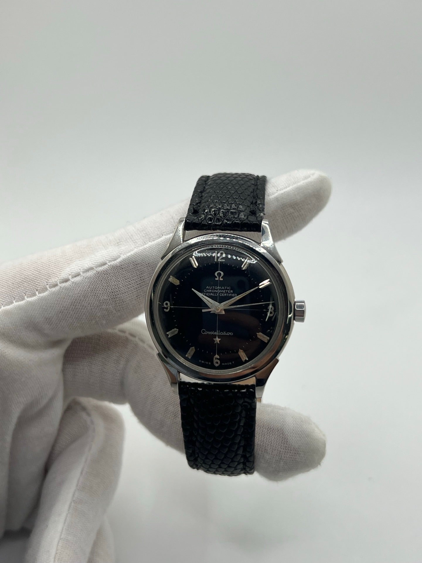 Montre automatique vintage en acier avec boîtier rond de 35 mm, cadran noir à chiffres arabes et verre plexiglas. Modèle chronomètre des années 1950 équipé d’un calibre automatique 505 avec réserve de marche de 46 heures. Bracelet en cuir noir avec boucle ardillon en acier. Montre d’occasion présentant des traces d’usure visibles, révisée récemment, sans coffret ni papiers d’origine.