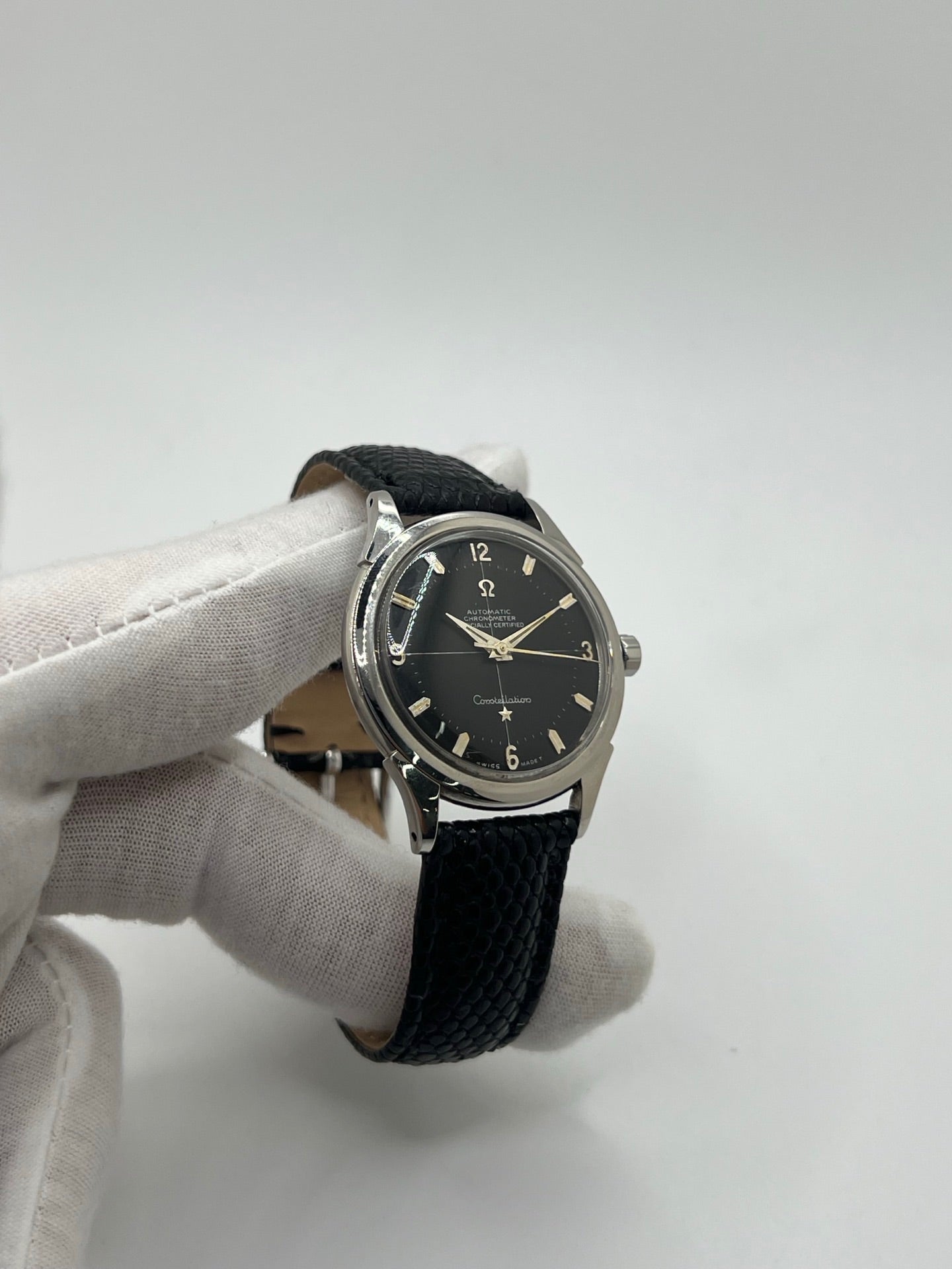 Montre automatique vintage en acier avec boîtier rond de 35 mm, cadran noir à chiffres arabes et verre plexiglas. Modèle chronomètre des années 1950 équipé d’un calibre automatique 505 avec réserve de marche de 46 heures. Bracelet en cuir noir avec boucle ardillon en acier. Montre d’occasion présentant des traces d’usure visibles, révisée récemment, sans coffret ni papiers d’origine.