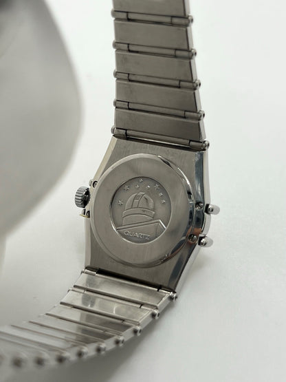 Montre Omega Constellation Quartz réf. 795.0876, modèle femme vintage en acier, mouvement quartz précis, boîtier et bracelet acier inoxydable, cadran argent massif sans chiffres, verre saphir. Dimensions 23 x 26 mm. Année 1985, état très bon avec légères traces d’usage peu visibles. Montre de luxe d’occasion, révisée en interne le 23 avril 2026. Sans boîte ni papiers d’origine, disponible à Paris. Pièce d’horlogerie suisse de collection Constellation.
