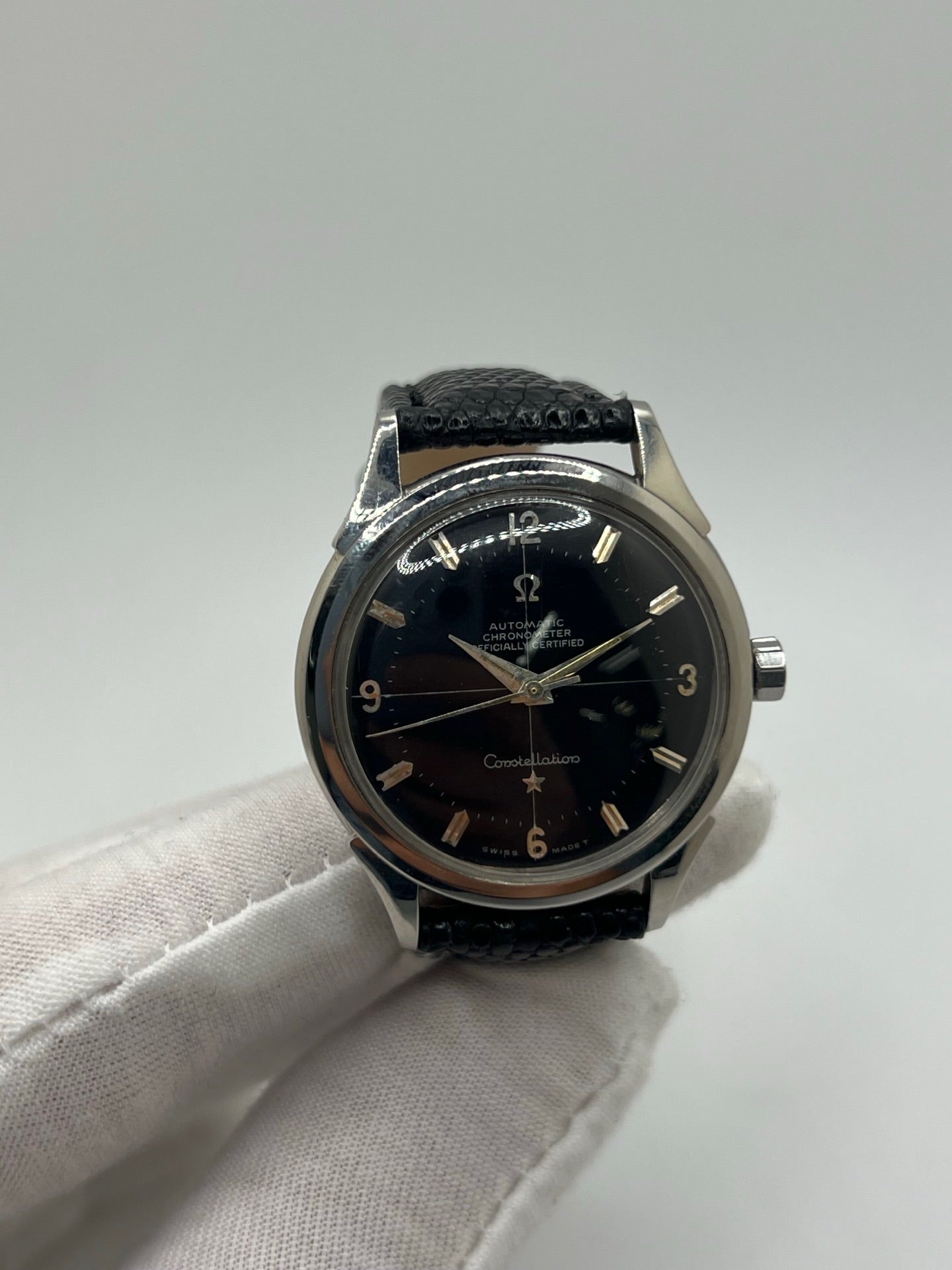 Montre automatique vintage en acier avec boîtier rond de 35 mm, cadran noir à chiffres arabes et verre plexiglas. Modèle chronomètre des années 1950 équipé d’un calibre automatique 505 avec réserve de marche de 46 heures. Bracelet en cuir noir avec boucle ardillon en acier. Montre d’occasion présentant des traces d’usure visibles, révisée récemment, sans coffret ni papiers d’origine.