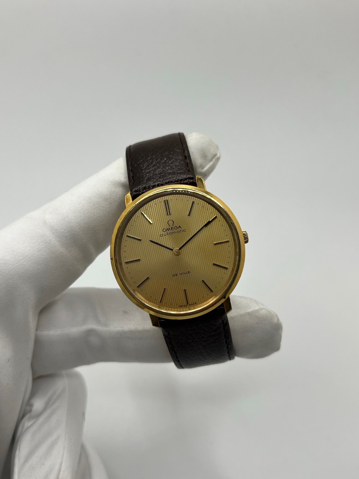 Montre Omega De Ville référence 151.0039 vintage de 1973 en acier avec mouvement automatique calibre 711, cadran doré et bracelet en cuir noir. Ce modèle homme ou unisexe de 35,5 mm présente un design élégant et intemporel. Montre d’occasion en très bon état, révisée en interne le 13 mars 2026, avec légères traces d’usure discrètes. Pièce classique de collection sans coffret ni papiers d’origine.