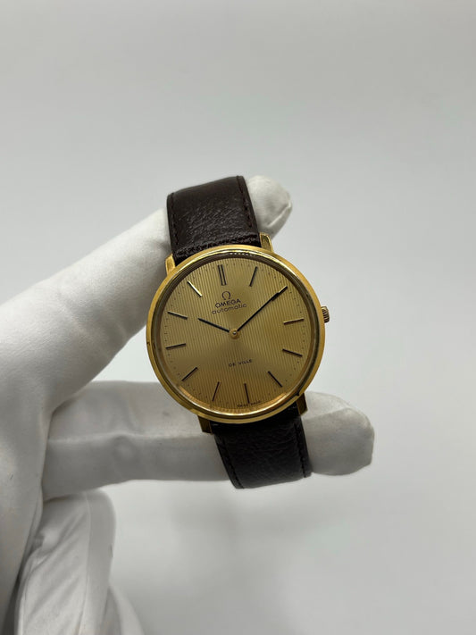 Montre Omega De Ville référence 151.0039 vintage de 1973 en acier avec mouvement automatique calibre 711, cadran doré et bracelet en cuir noir. Ce modèle homme ou unisexe de 35,5 mm présente un design élégant et intemporel. Montre d’occasion en très bon état, révisée en interne le 13 mars 2026, avec légères traces d’usure discrètes. Pièce classique de collection sans coffret ni papiers d’origine.