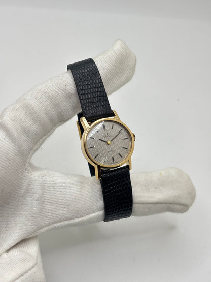 Montre Omega De Ville vintage référence 511.0508 pour femme, datant de 1967, avec boîtier en acier de 24 mm et cadran gris à index bâtons. Cette montre à remontage manuel est équipée du calibre Omega 625 à 17 rubis et est montée sur un bracelet en cuir noir avec boucle ardillon en acier. Révisée et en très bon état, elle présente de légères traces d'usure conformes à son âge. Une montre de collection au design élégant, idéale pour les amateurs d'horlogerie vintage.