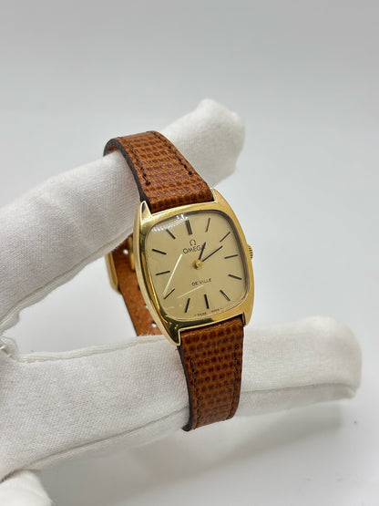Montre Omega De Ville vintage référence 511.0531 en plaqué or datant de 1969, équipée d'un mouvement à remontage manuel. Son cadran doré à index bâtons est protégé par un verre en matière plastique. Son boîtier de 25 mm est associé à un bracelet en cuir brun avec boucle ardillon en acier. Cette montre d'occasion, révisée et en très bon état, séduit par son élégance intemporelle et son style classique des années 1960.