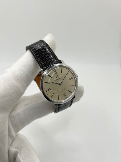 Montre Omega De Ville vintage référence 111.077 en acier, fabriquée en 1969. Ce modèle à remontage manuel est doté d'un cadran argent avec chiffres romains, d'un verre en plexiglas et d'un boîtier de 33 mm. Le bracelet en cuir noir avec boucle ardillon en acier complète son style classique et intemporel. Cette montre d'occasion révisée séduit les amateurs d'horlogerie vintage et de montres Omega de collection.
