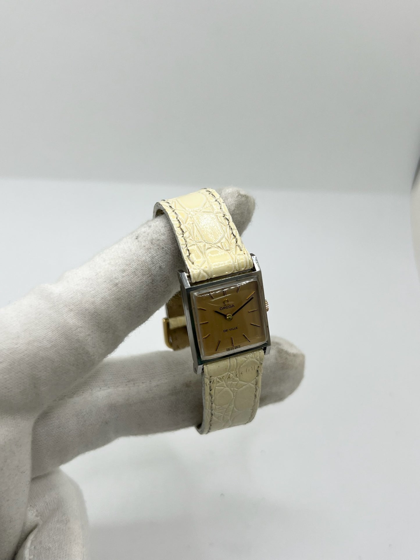 Montre Omega De Ville 511.087 vintage pour femme en acier, fabriquée en 1966. Cette montre élégante est dotée d'un cadran champagne avec index bâtons, d'un mouvement à remontage manuel calibre 620 et d'un verre en plexiglas. Elle est montée sur un bracelet en cuir beige avec boucle ardillon en acier. Son format de 19,5 mm lui confère une allure raffinée et intemporelle. Montre de collection en très bon état d'occasion, révisée et prête à être portée.