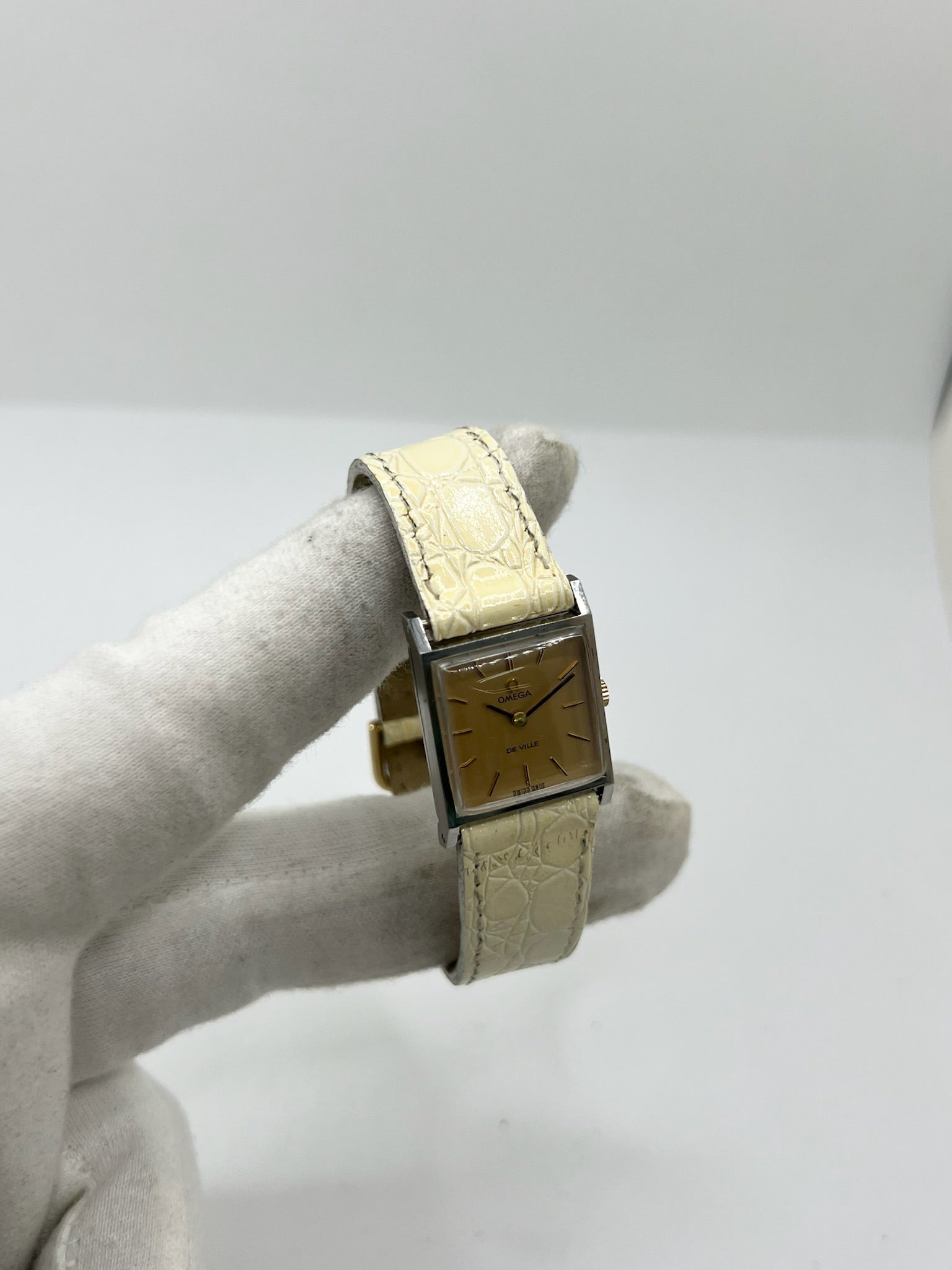 Montre Omega De Ville 511.087 vintage pour femme en acier, fabriquée en 1966. Cette montre élégante est dotée d'un cadran champagne avec index bâtons, d'un mouvement à remontage manuel calibre 620 et d'un verre en plexiglas. Elle est montée sur un bracelet en cuir beige avec boucle ardillon en acier. Son format de 19,5 mm lui confère une allure raffinée et intemporelle. Montre de collection en très bon état d'occasion, révisée et prête à être portée.