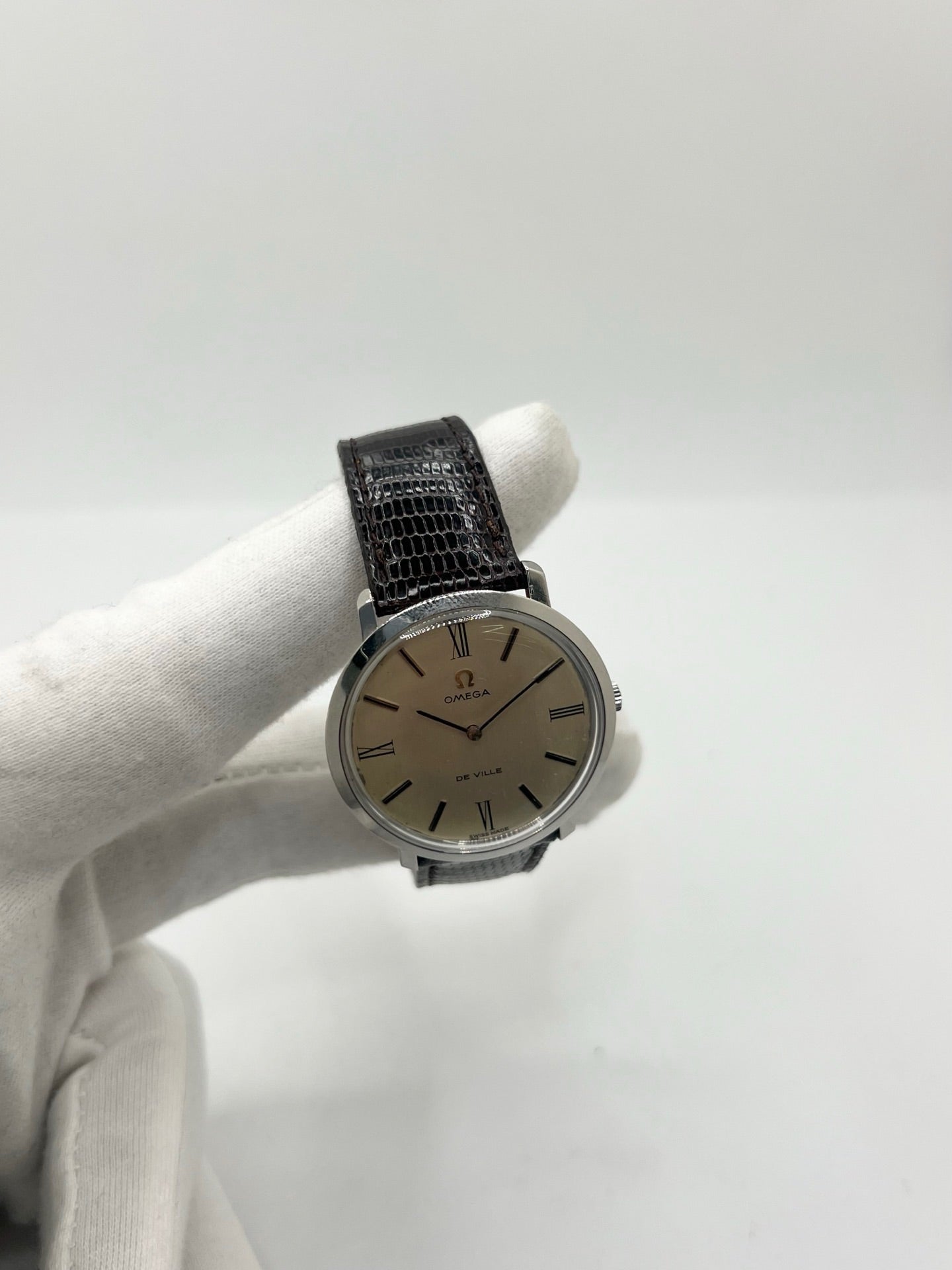 Montre Omega De Ville vintage référence 111.077 en acier, fabriquée en 1969. Ce modèle à remontage manuel est doté d'un cadran argent avec chiffres romains, d'un verre en plexiglas et d'un boîtier de 33 mm. Le bracelet en cuir noir avec boucle ardillon en acier complète son style classique et intemporel. Cette montre d'occasion révisée séduit les amateurs d'horlogerie vintage et de montres Omega de collection.

