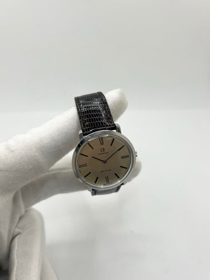 Montre Omega De Ville vintage référence 111.077 en acier, fabriquée en 1969. Ce modèle à remontage manuel est doté d'un cadran argent avec chiffres romains, d'un verre en plexiglas et d'un boîtier de 33 mm. Le bracelet en cuir noir avec boucle ardillon en acier complète son style classique et intemporel. Cette montre d'occasion révisée séduit les amateurs d'horlogerie vintage et de montres Omega de collection.
