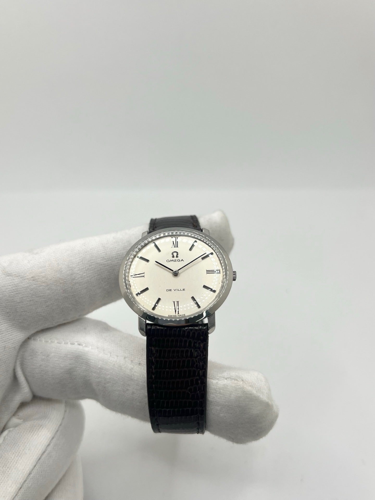 Montre Omega De Ville vintage référence 111.077 en acier, fabriquée en 1969. Ce modèle à remontage manuel est doté d'un cadran argent avec chiffres romains, d'un verre en plexiglas et d'un boîtier de 33 mm. Le bracelet en cuir noir avec boucle ardillon en acier complète son style classique et intemporel. Cette montre d'occasion révisée séduit les amateurs d'horlogerie vintage et de montres Omega de collection.
