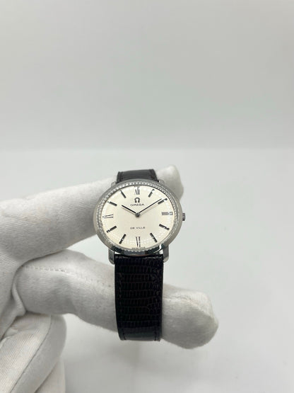 Montre Omega De Ville vintage référence 111.077 en acier, fabriquée en 1969. Ce modèle à remontage manuel est doté d'un cadran argent avec chiffres romains, d'un verre en plexiglas et d'un boîtier de 33 mm. Le bracelet en cuir noir avec boucle ardillon en acier complète son style classique et intemporel. Cette montre d'occasion révisée séduit les amateurs d'horlogerie vintage et de montres Omega de collection.
