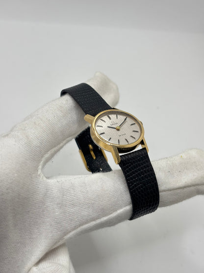 Montre Omega De Ville vintage référence 511.0508 pour femme, datant de 1967, avec boîtier en acier de 24 mm et cadran gris à index bâtons. Cette montre à remontage manuel est équipée du calibre Omega 625 à 17 rubis et est montée sur un bracelet en cuir noir avec boucle ardillon en acier. Révisée et en très bon état, elle présente de légères traces d'usure conformes à son âge. Une montre de collection au design élégant, idéale pour les amateurs d'horlogerie vintage.